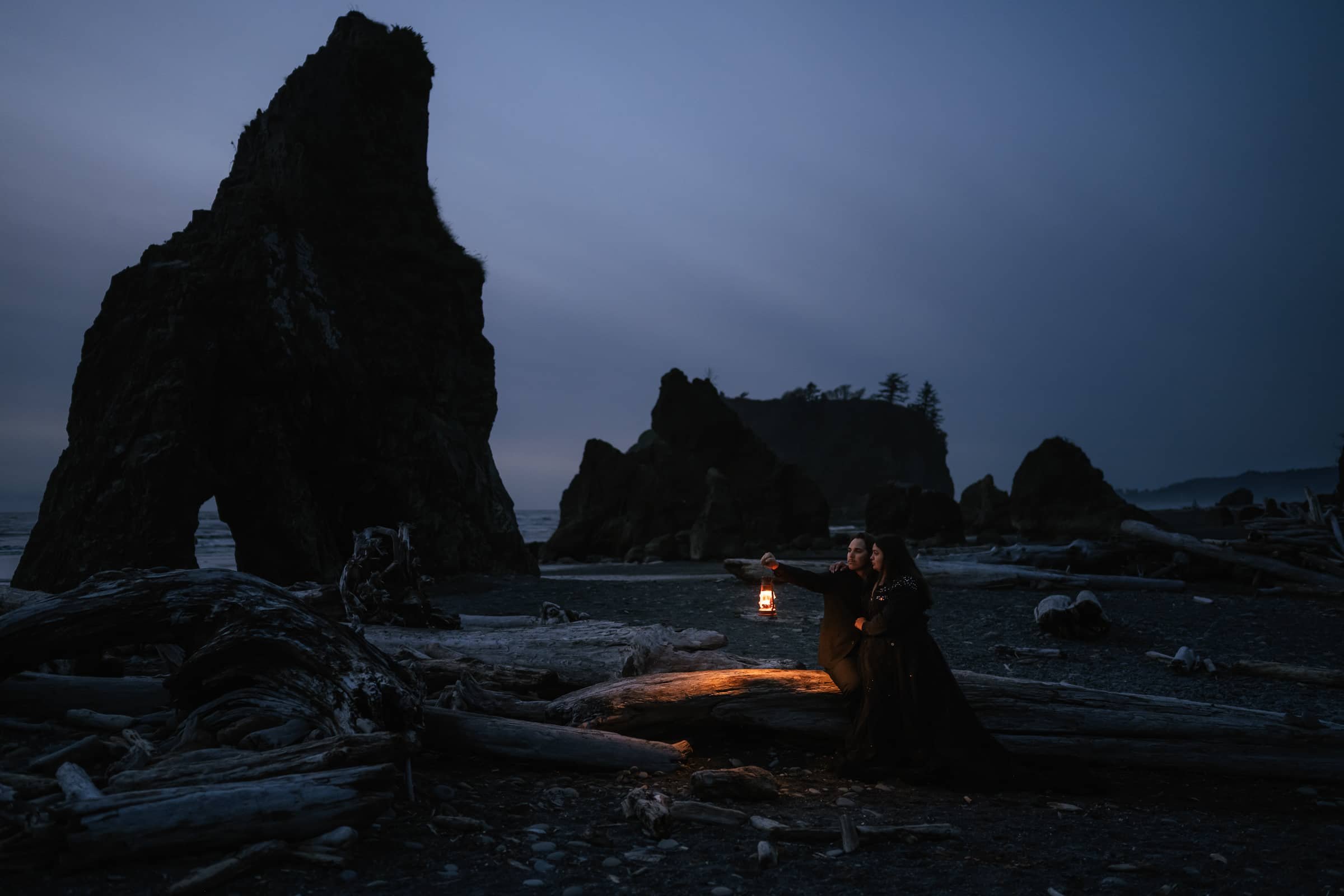 groom holds lantern for moody wedding photo on ruby beach