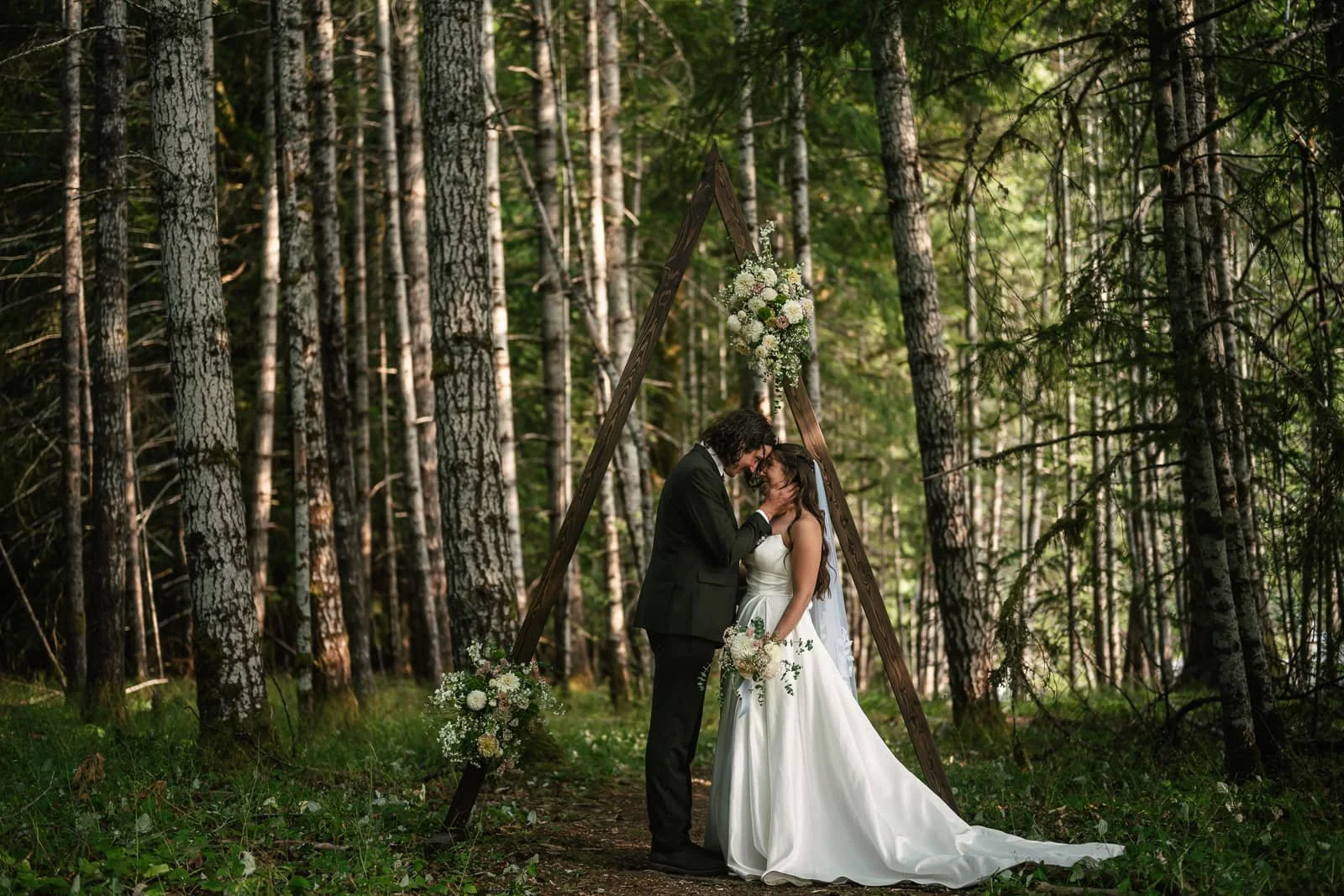 couple poses under wooden arch in birch forest at bovee meadow