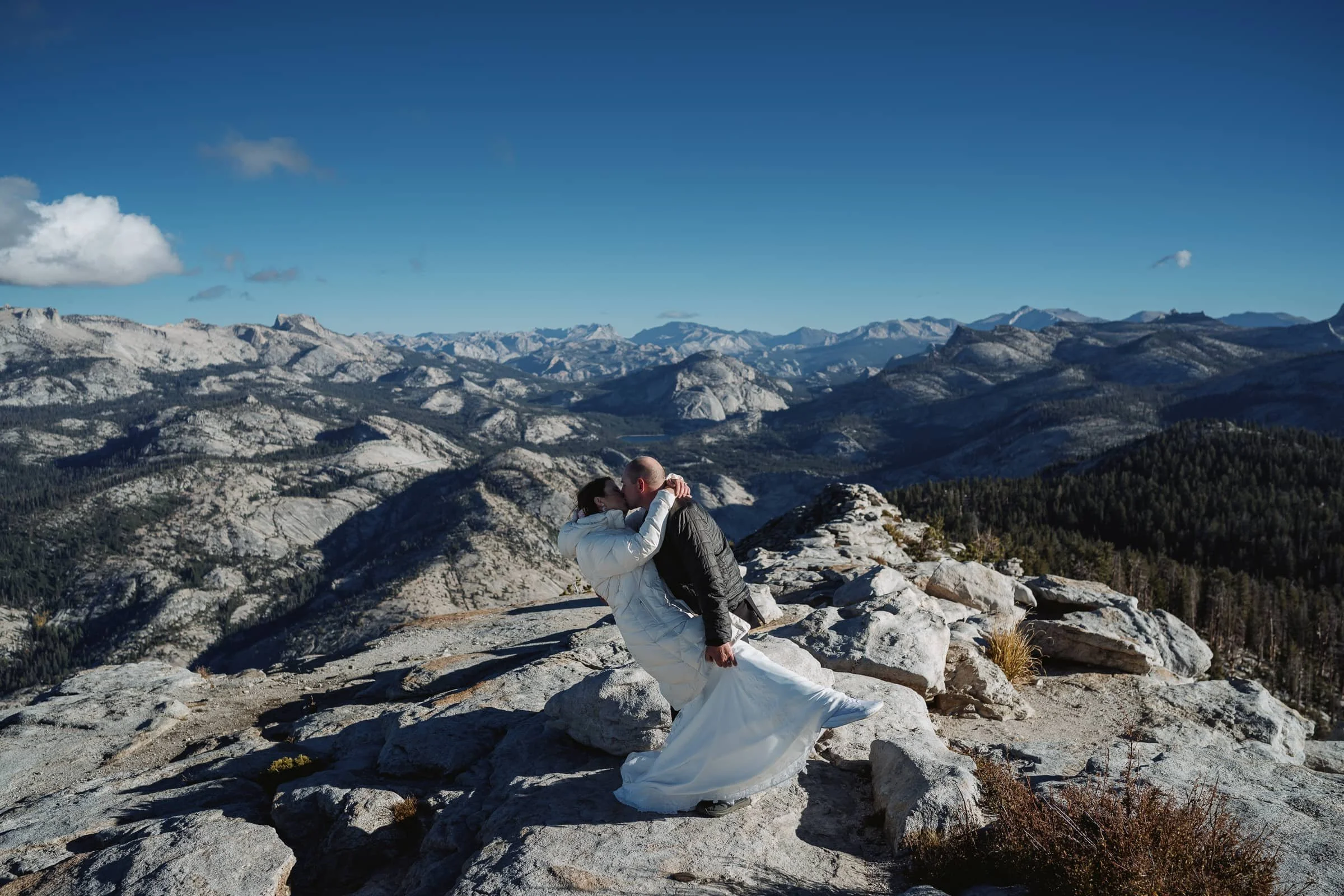 Groom dips wife in wedding dress on the ridge of Clouds rest