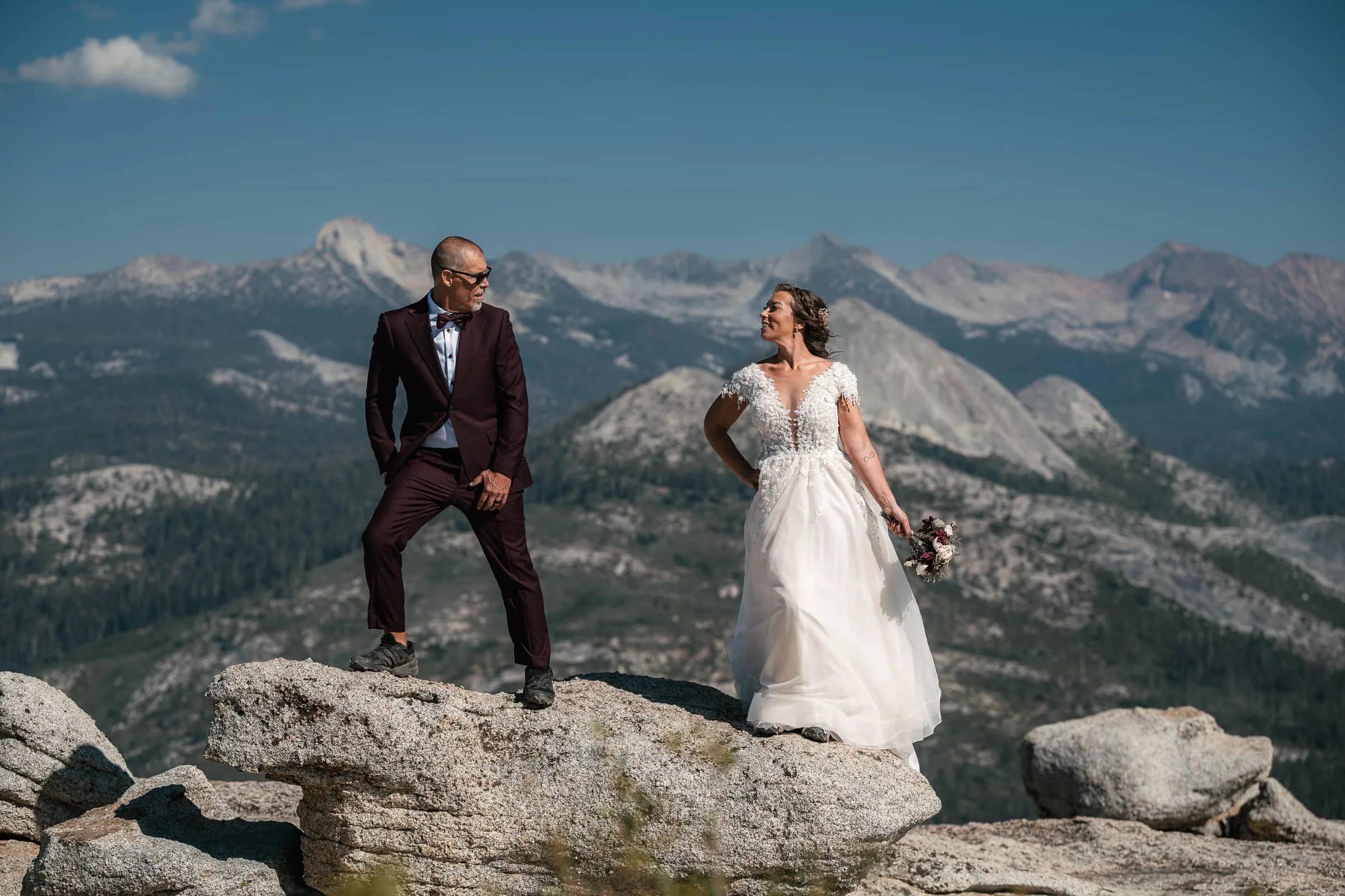 couple poses on sentinel dome at their yosemite wedding maroon suit