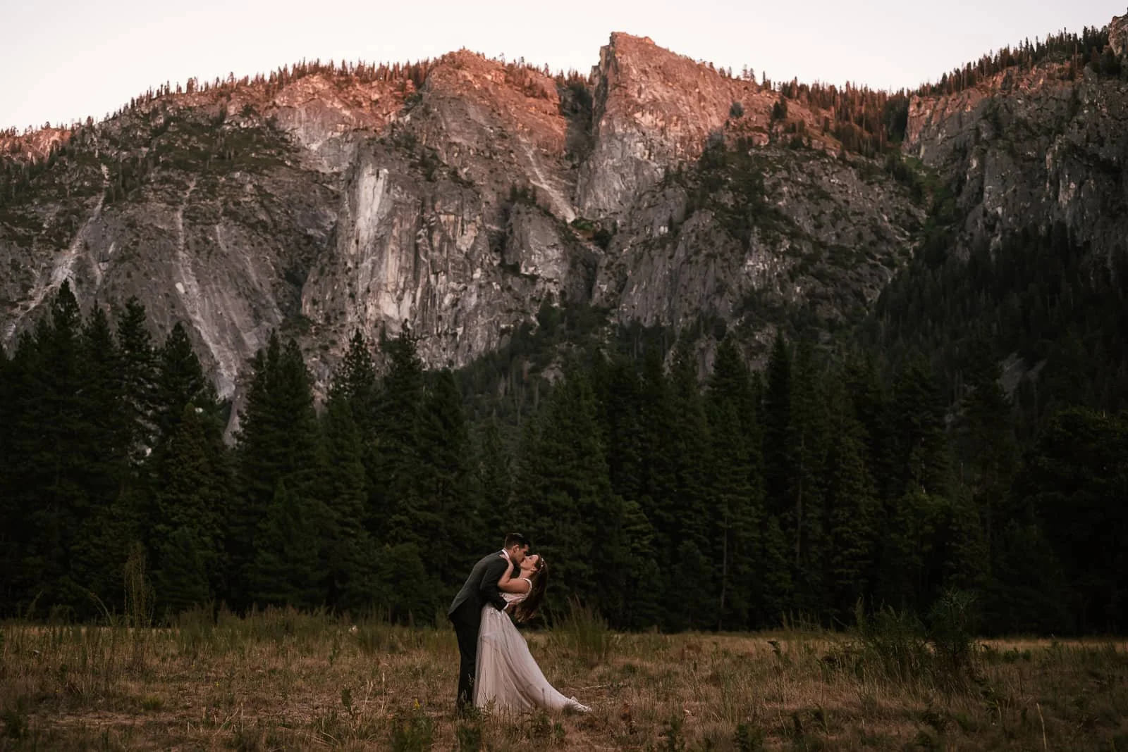 groom dips his new wife in a yosemite meadow at sunset