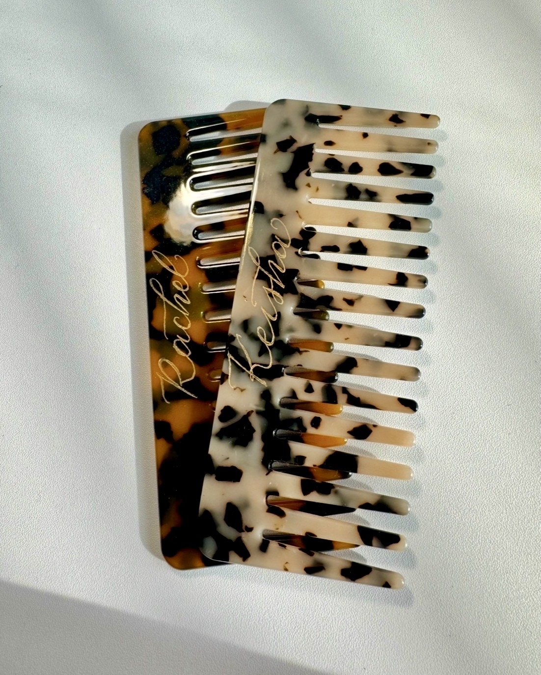 Two decorative hair combs with tortoiseshell pattern on a white surface. One comb has the name 'Rachel' written on it, and the other has the name 'Keisha' written on it, in a cursive style.