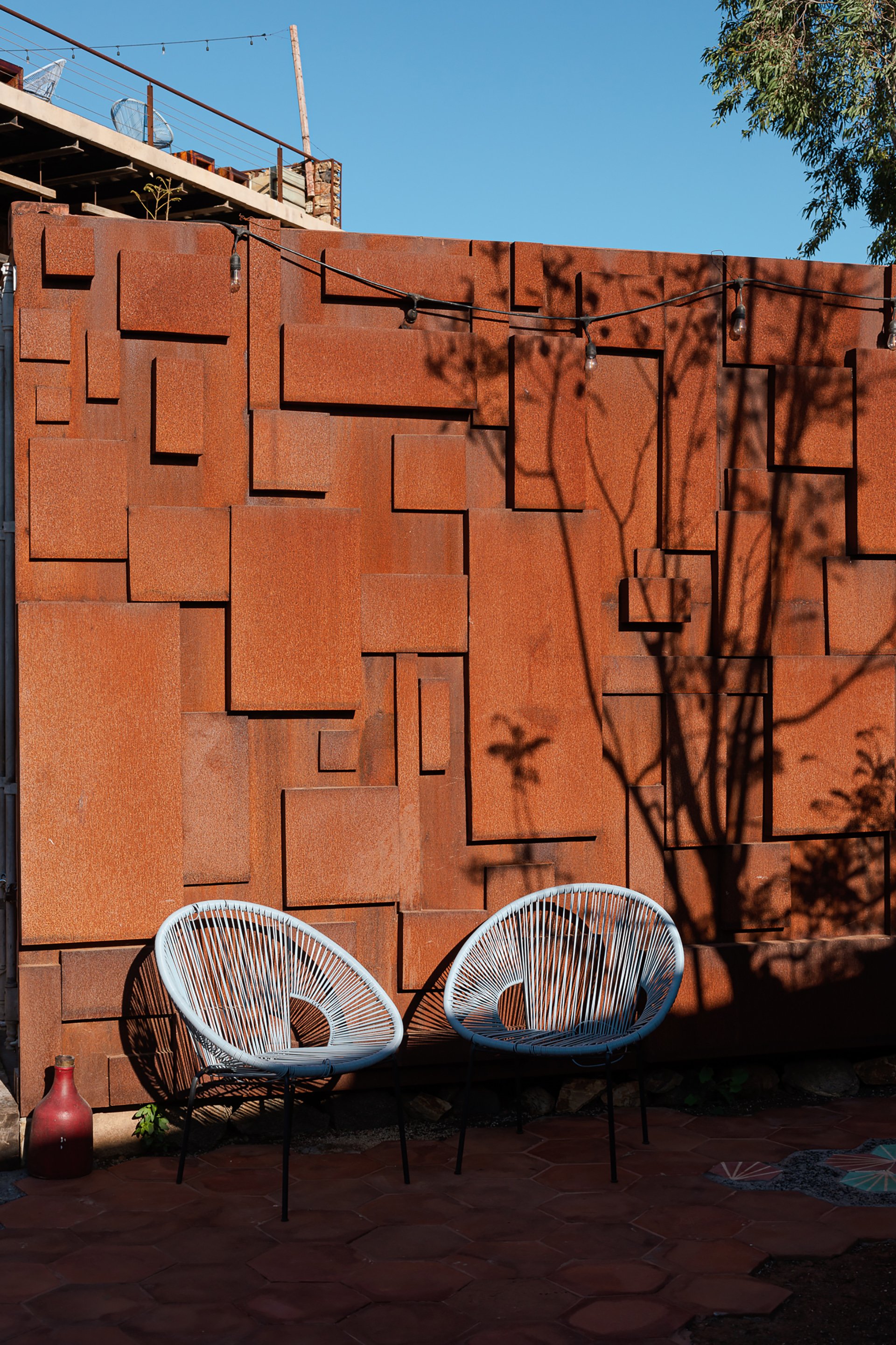 A tranquil outdoor seating area framed by olive trees, with rustic stone and handcrafted wooden furniture. This space is ideal for boutique hotels and sustainable hospitality in Melbourne and New Zealand. My focus on sustainability and spaces photogr