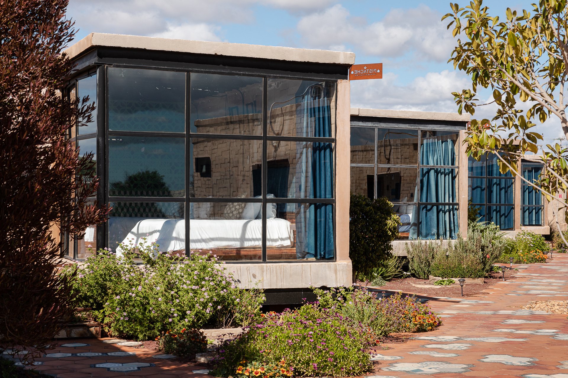 Modern glass-walled suites surrounded by colorful gardens and native plants, blending luxury with eco-consciousness. Perfect for boutique hotels in Melbourne and New Zealand. My photography highlights the sustainability and aesthetic appeal of these
