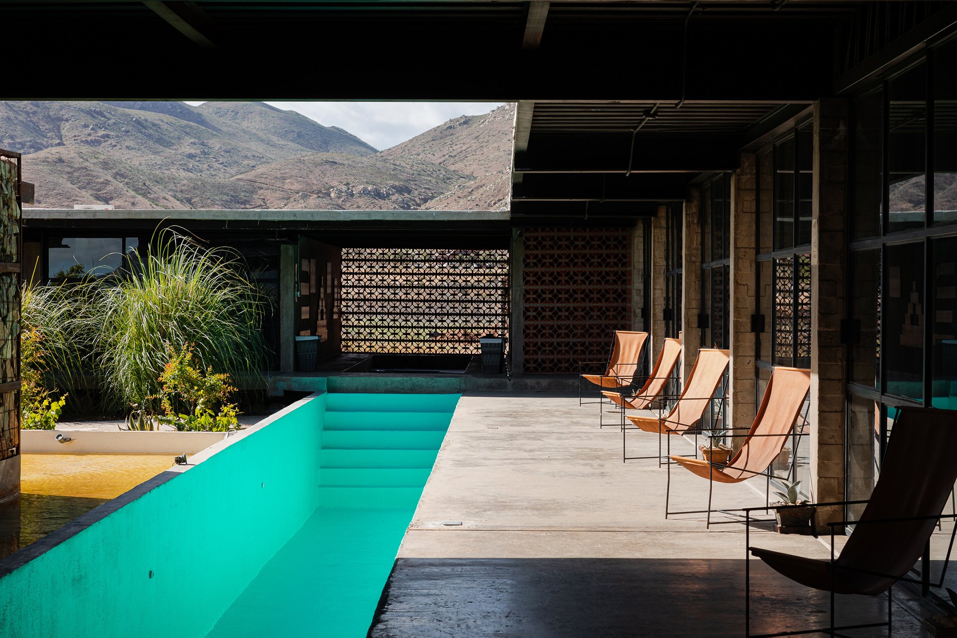 A minimalist poolside seating area with panoramic mountain views, designed for boutique hotels focused on offering serene and design-forward experiences. I specialize in showcasing the architectural elegance and natural harmony of spaces across Mexic