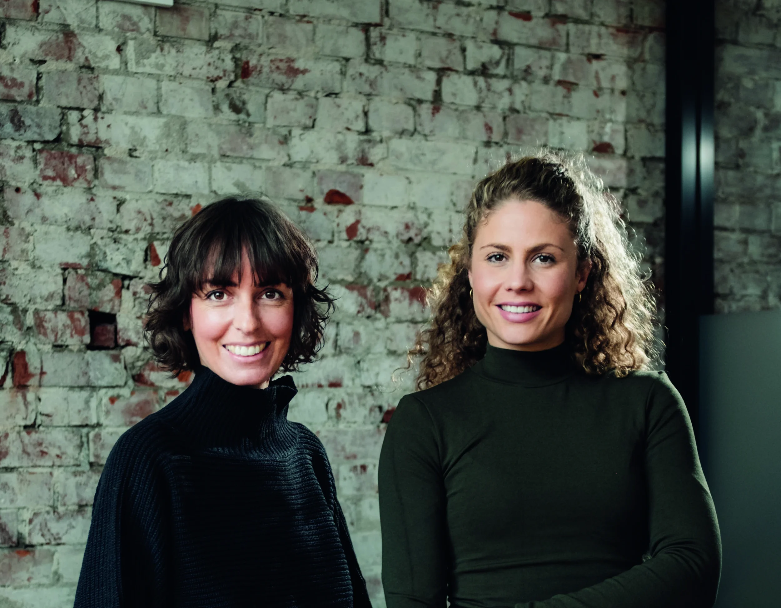 Natalie und Mar von therefore beauty stehen vor einer Wand und lächeln in die Kamera