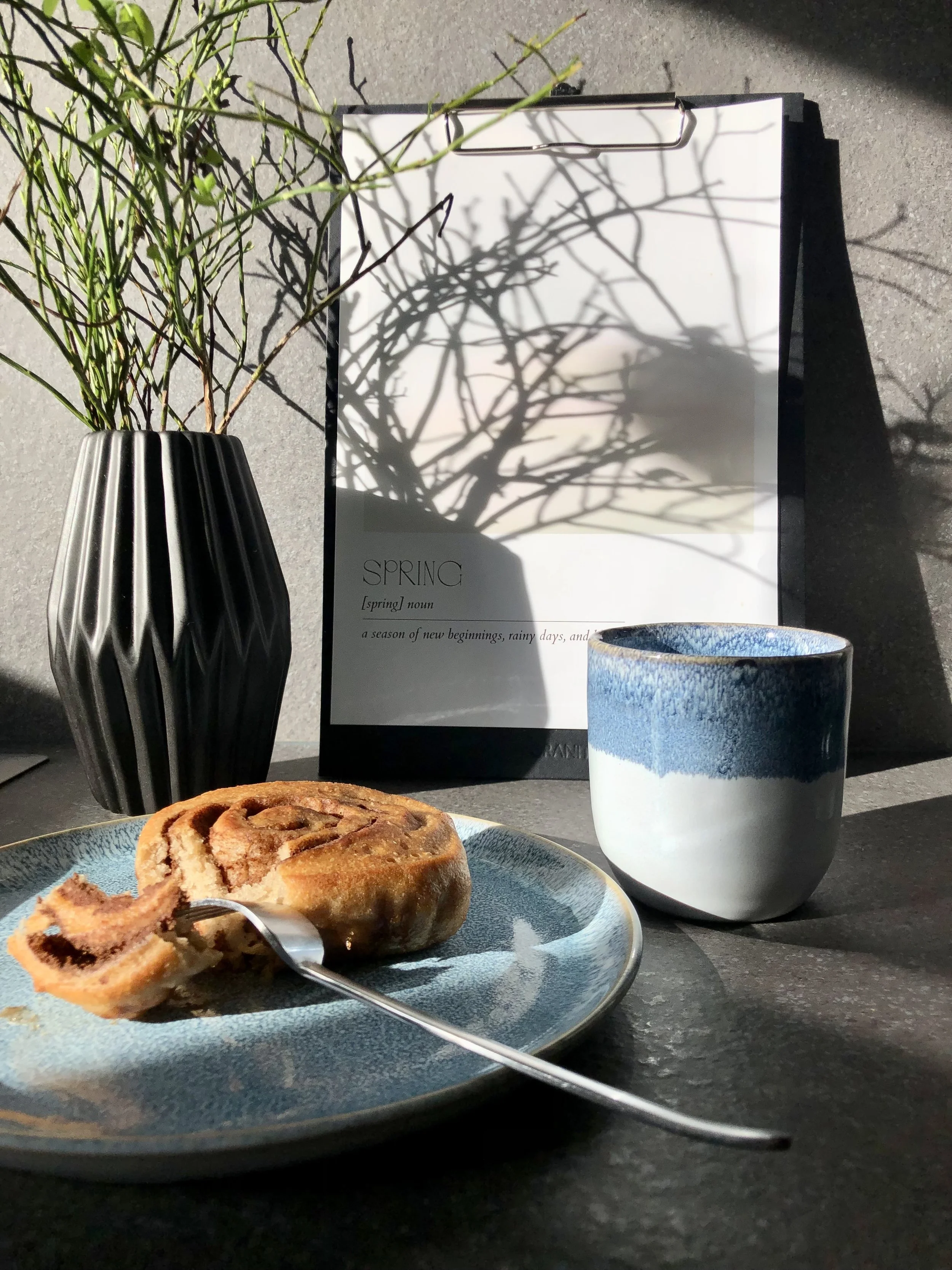 Glutenfreie Zimtschnecke von echt jetzt auf einem Teller, daneben ein Becher Kaffee