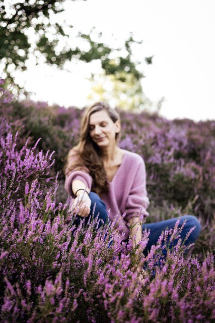 Die Yoga-Lehrerin Kerstin Mattmüller sitzt inmitten der blühenden Heidelandschaft