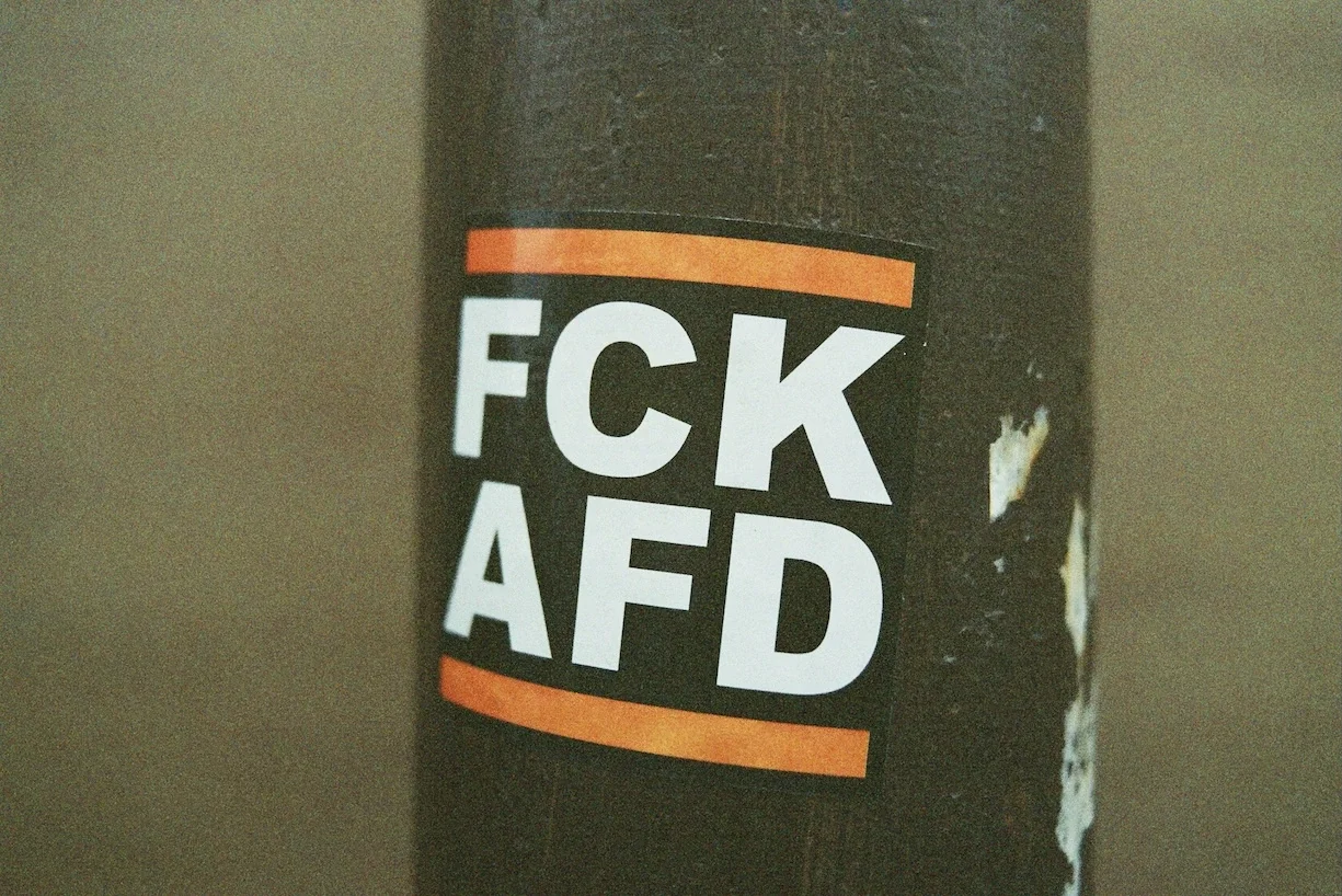 Ein Aufkleber ist an einem Laternenpfahl zu sehen, darauf steht "FCK AFD"