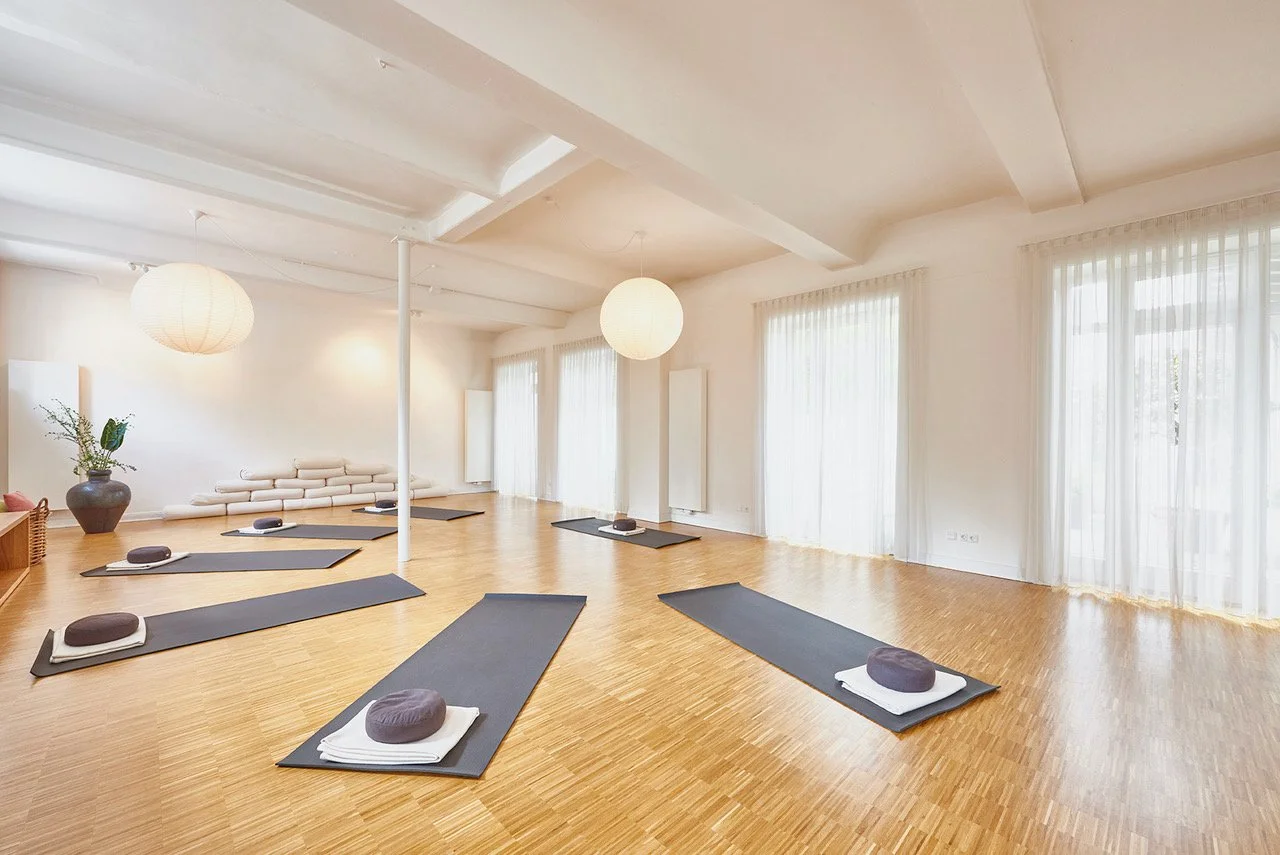 Das Yogastudio "Yoga im Hof" von innen, Yogamatten, Kissen und Decken  liegen auf einem schönen Holzboden