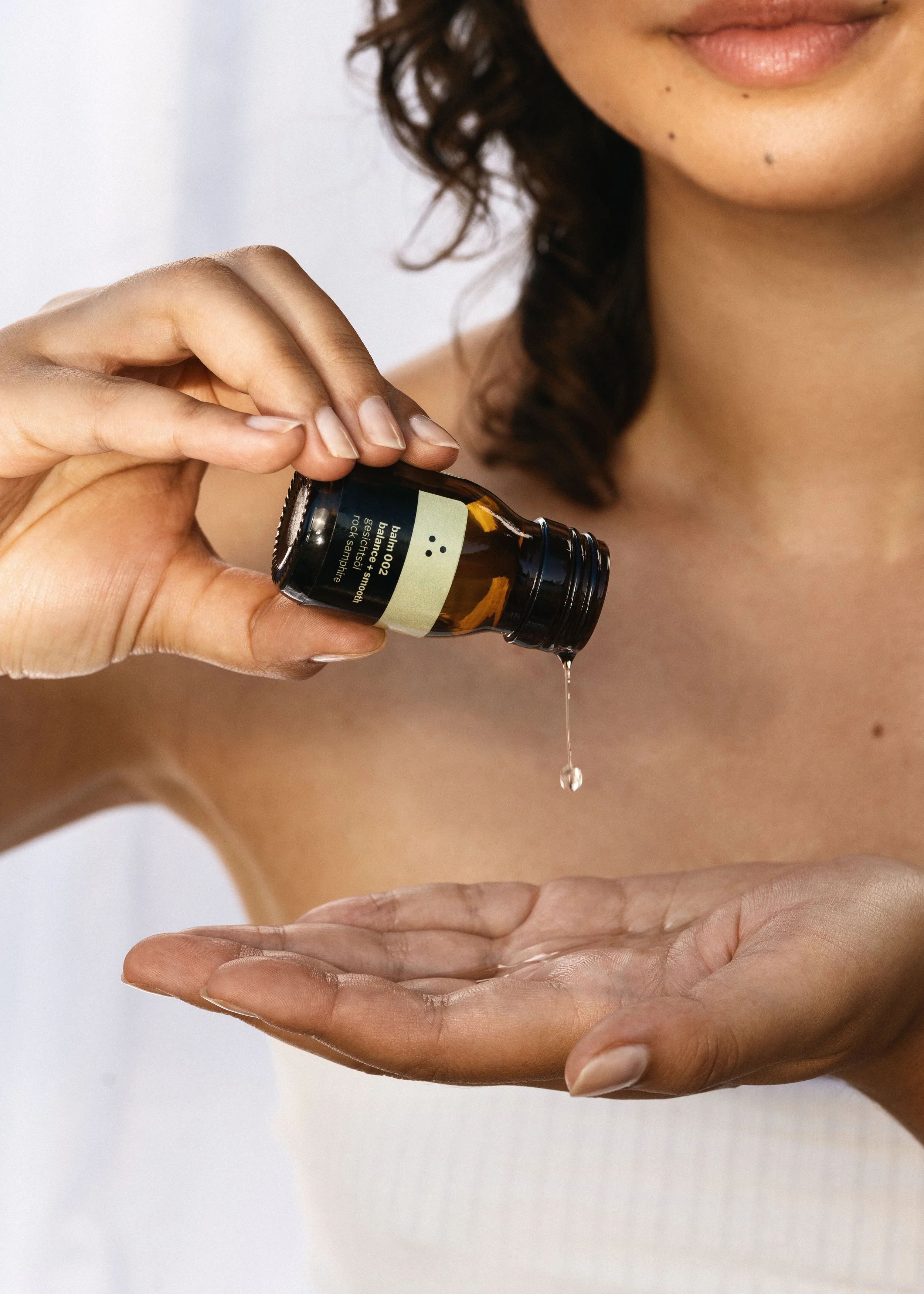 Ein weibliches Model tropft sich etwas von dem balm 002 der Marle therefore beauty auf die Hand