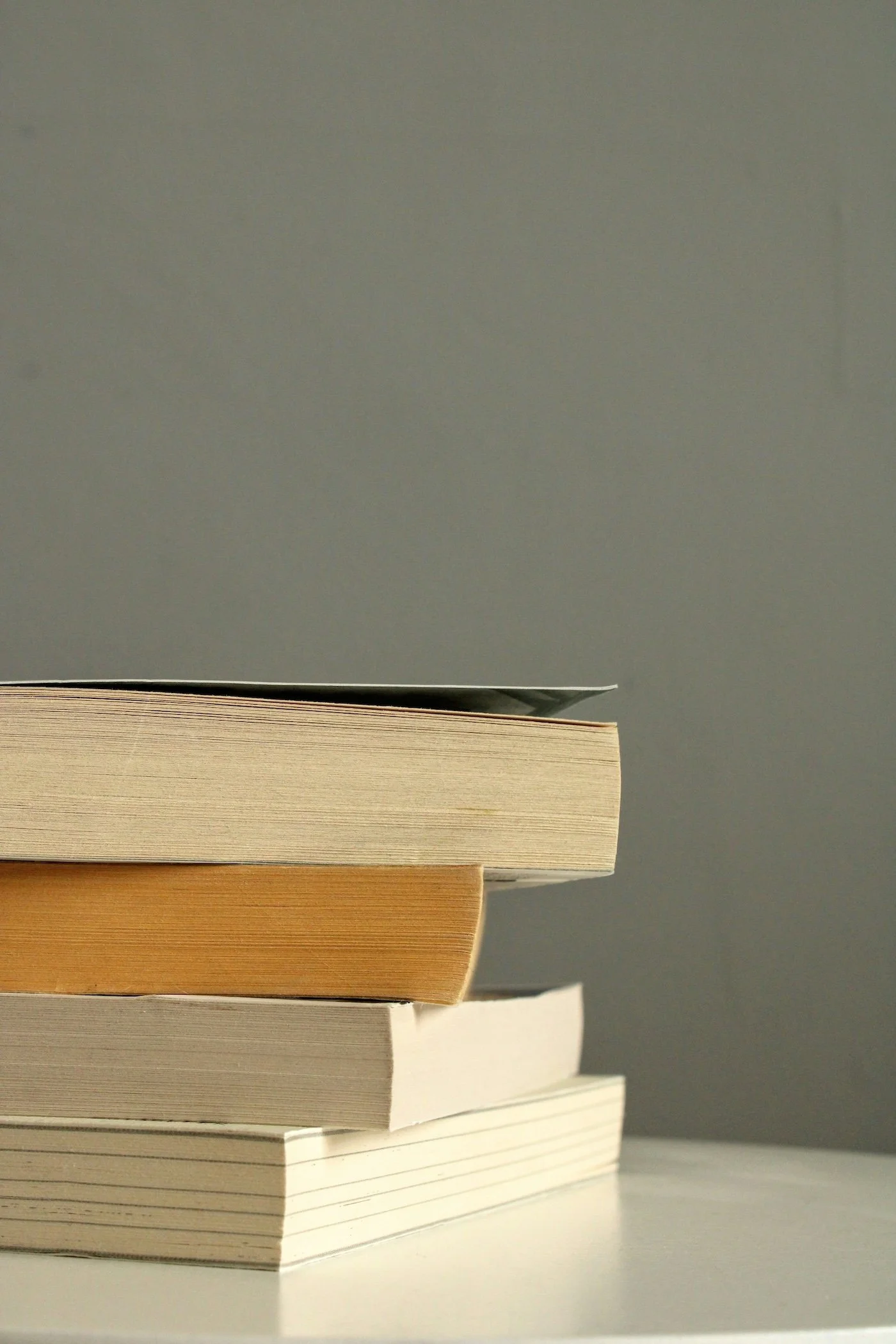Ein Buchstapel zeigt vier Bücher, auf einem Tisch liegend