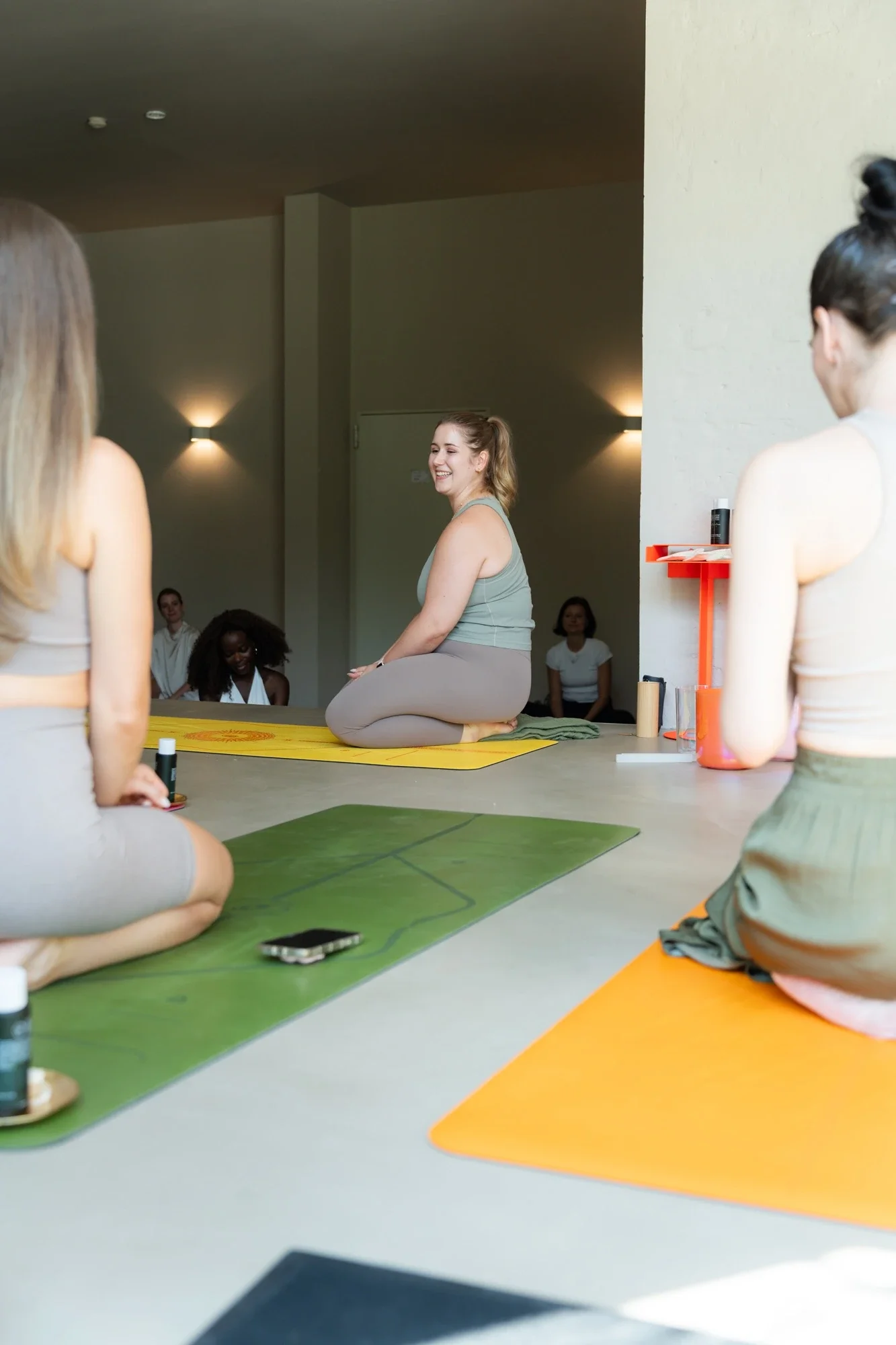Die Yogalehrerin Lena Jungmann gibt eine Yogaklasse, sie sitzt inmitten von Yoga-Schüler*innen
