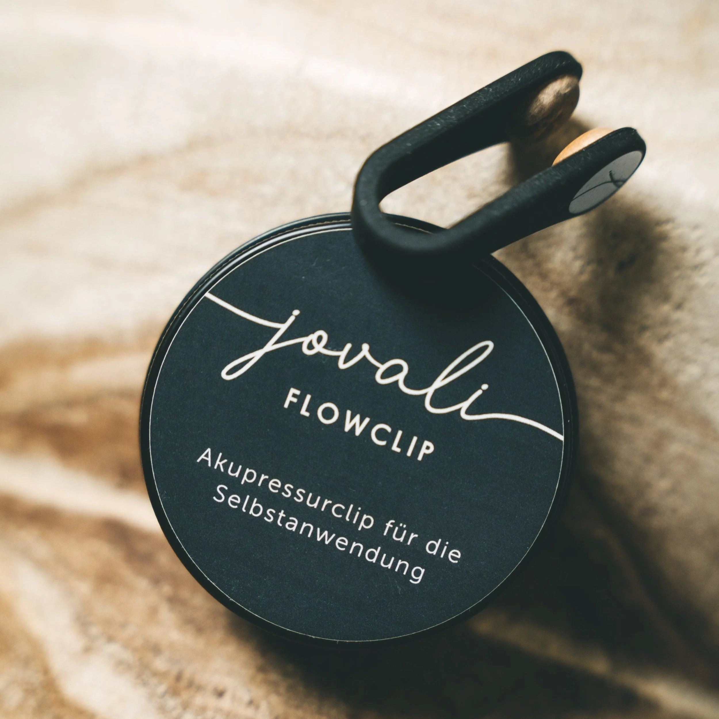 Der FlowClip von Jovali ist hier zu sehen und liegt auf der kreisrunden Verpackung