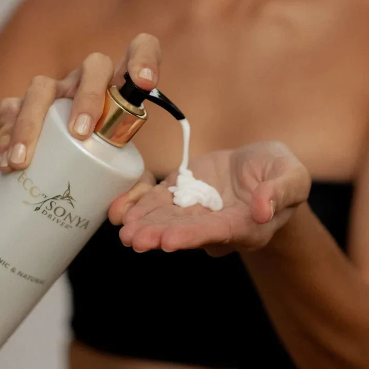 Eine FRau pumpt die Kokos-Bodylotion von Eco by Sonya auf ihre Hände