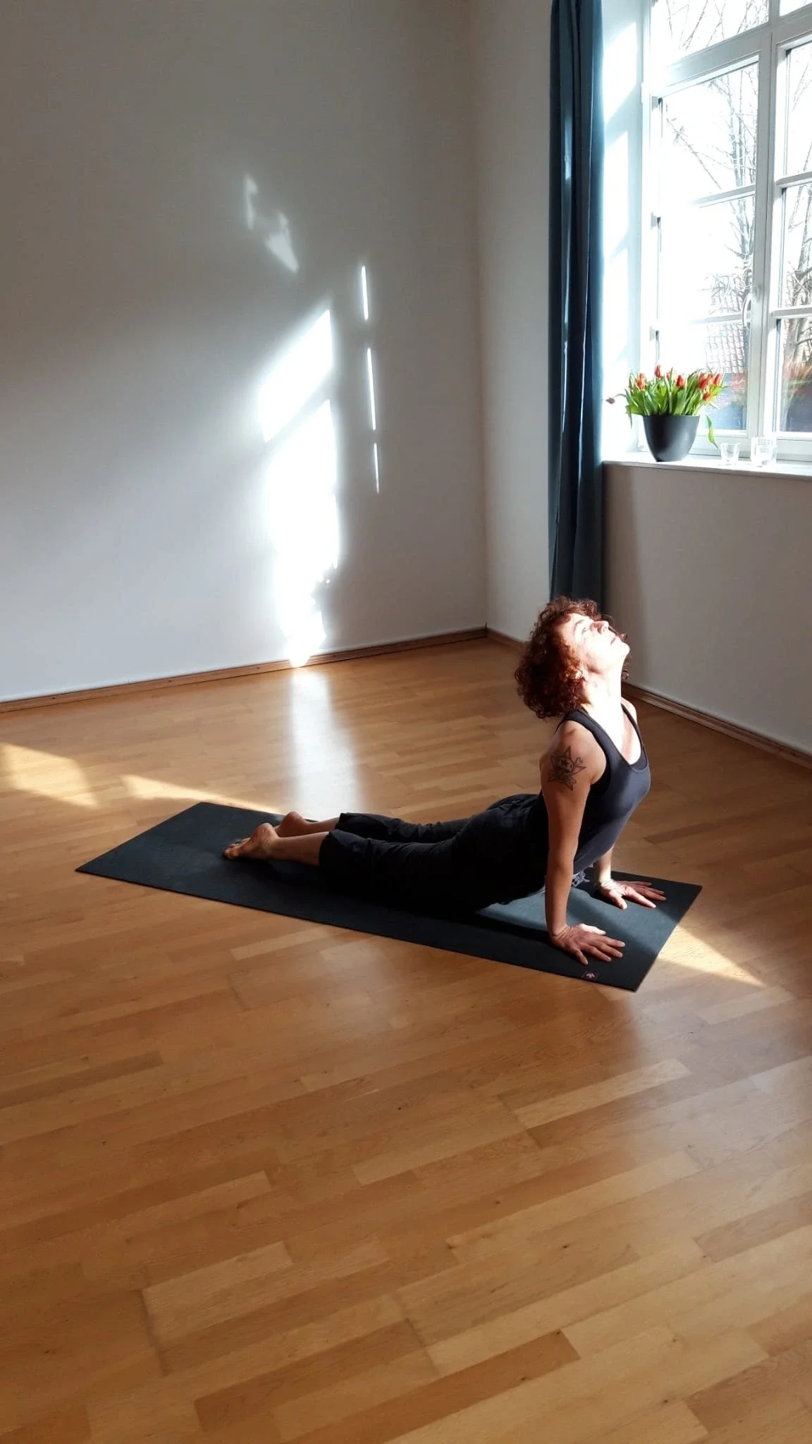 Die Yoga-Lehrerin Melanie Richtmann aus Hannover in der Yogapaso Kobra, sie ist in einem Yogastudio zu sehen, das Licht fällt auf sie