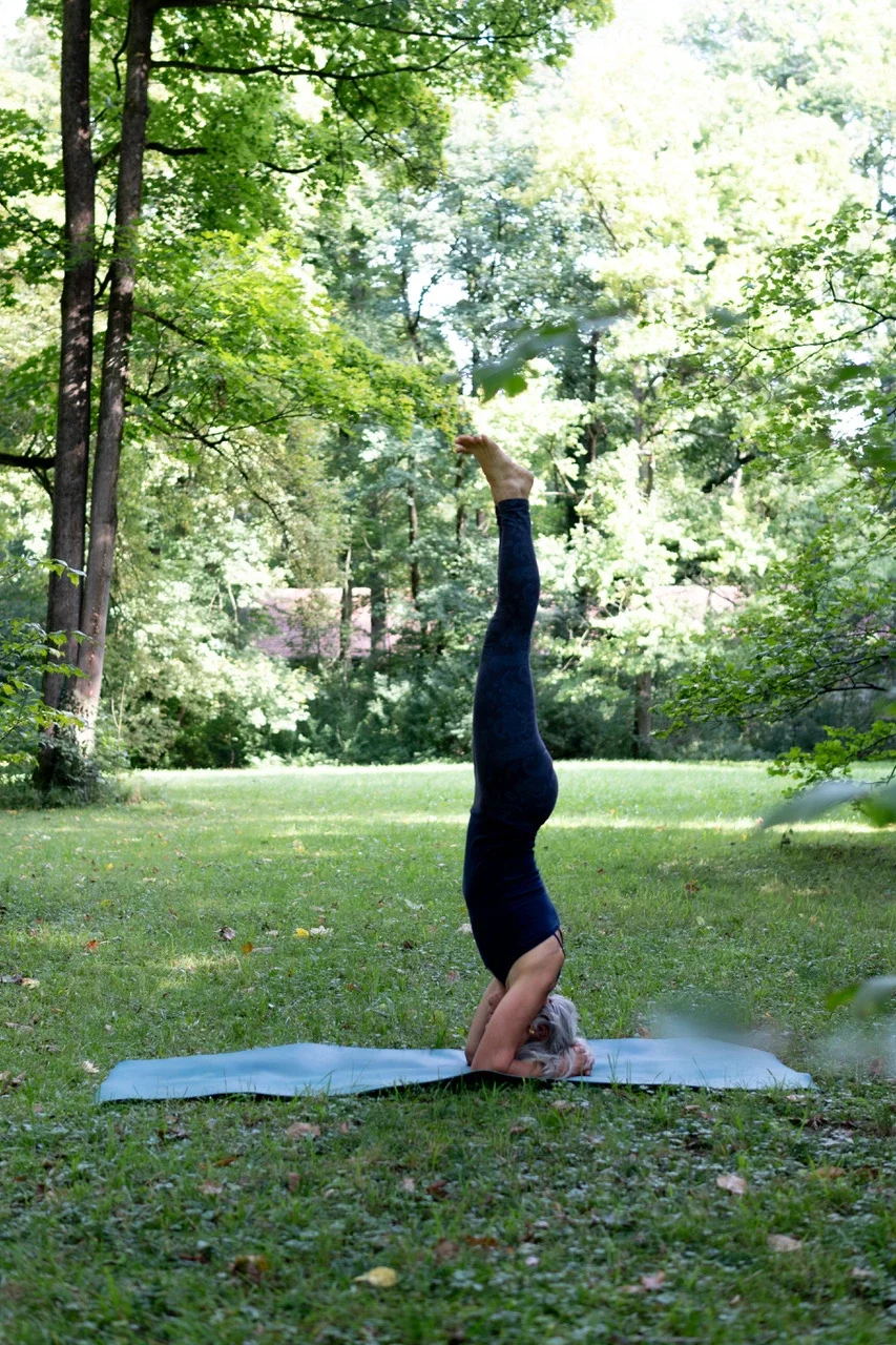 Die Yoga-Lehrerin Sabine Krieger im Kopfstand auf einer Matte im Park ist hier zu sehen
