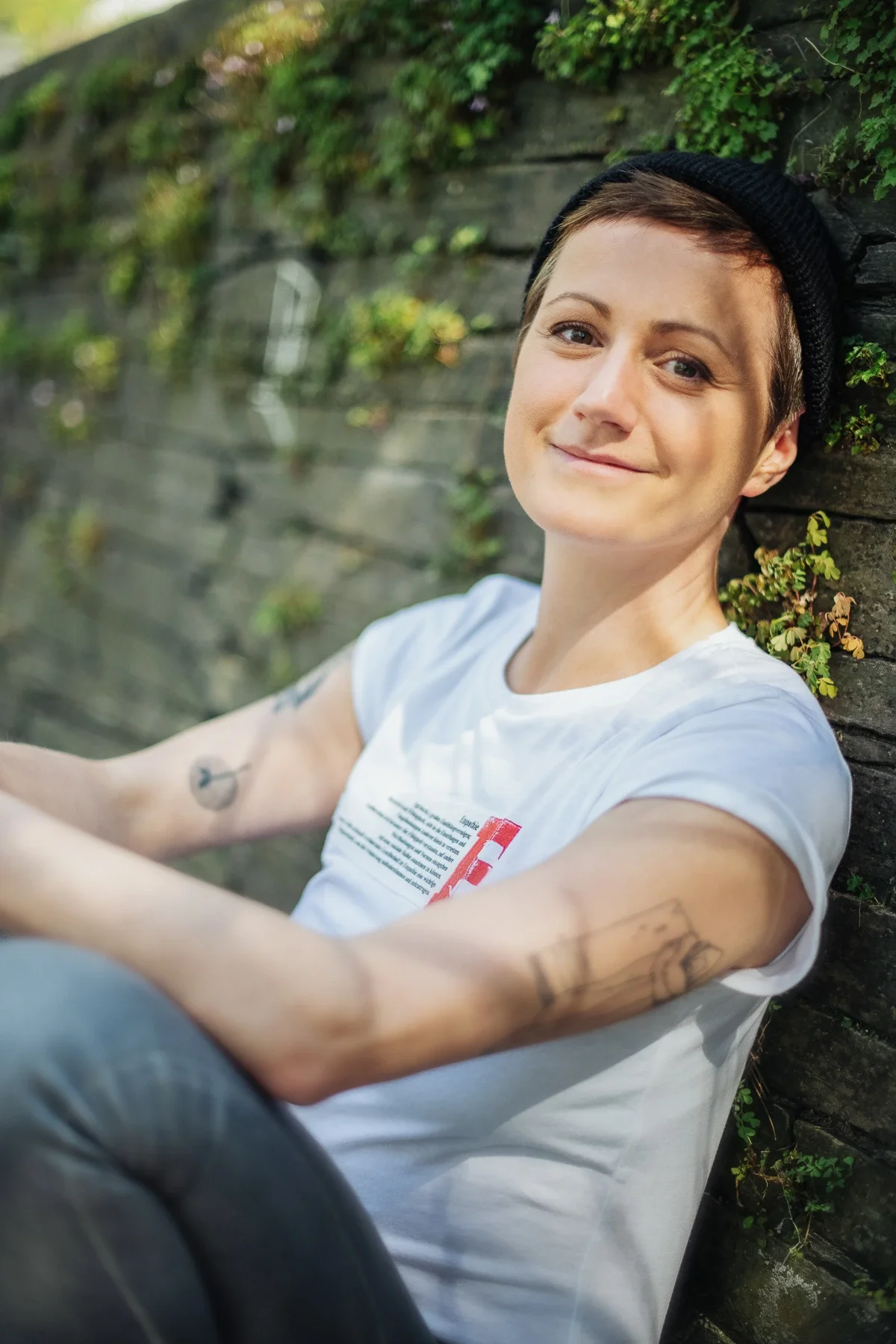 Die Yogalehrerin Tina Scheid sitzt an einer Mauer und sieht in die Kamera