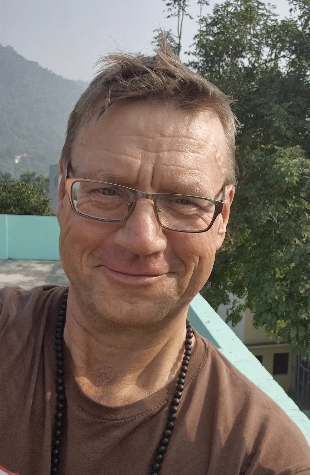 Der Yogalehrer Olaf Bohn aus Hamburg schaut in die Kamera, im Hintergrund ist Indien zu sehen