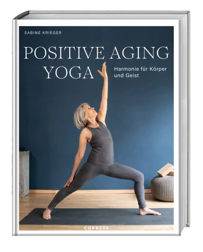 Das Cover zum Buch "Positive Aging Yoga" zeigt die Yoga-Lehrerin Sabine Krieger in einer Krieger-Position vor blauer Wand