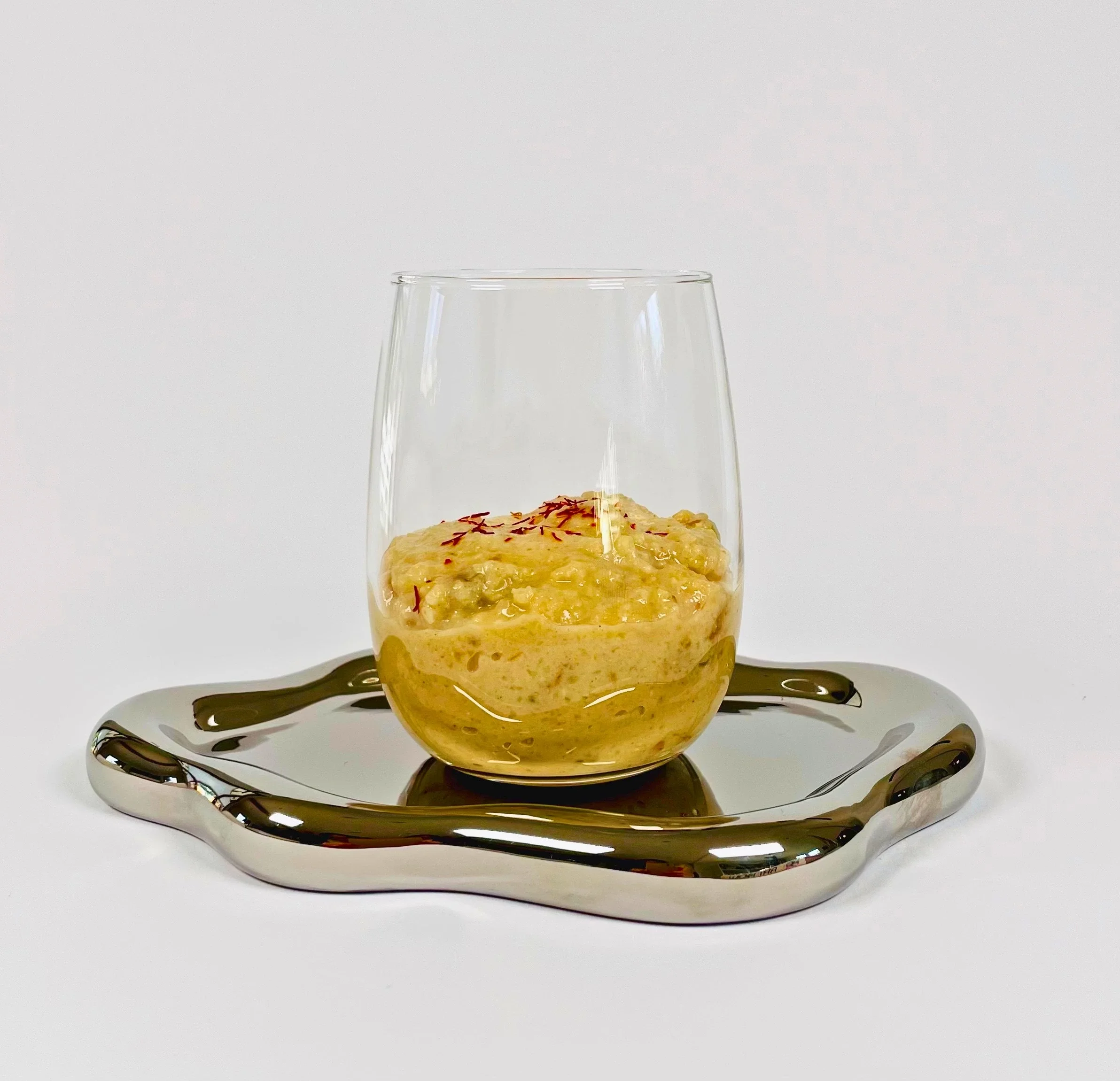 Ein Glas mit einem Hirse-Safran-Aprikosen-Frühstück mit InnoNature Vanille Mix Proteinpulver ist hier zu sehen