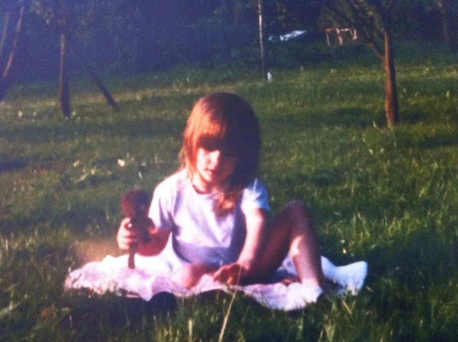 Die Bloggerin Julia Köcher-Eckebrecht sitzt als Kind auf einer Wiese, ca. 1980