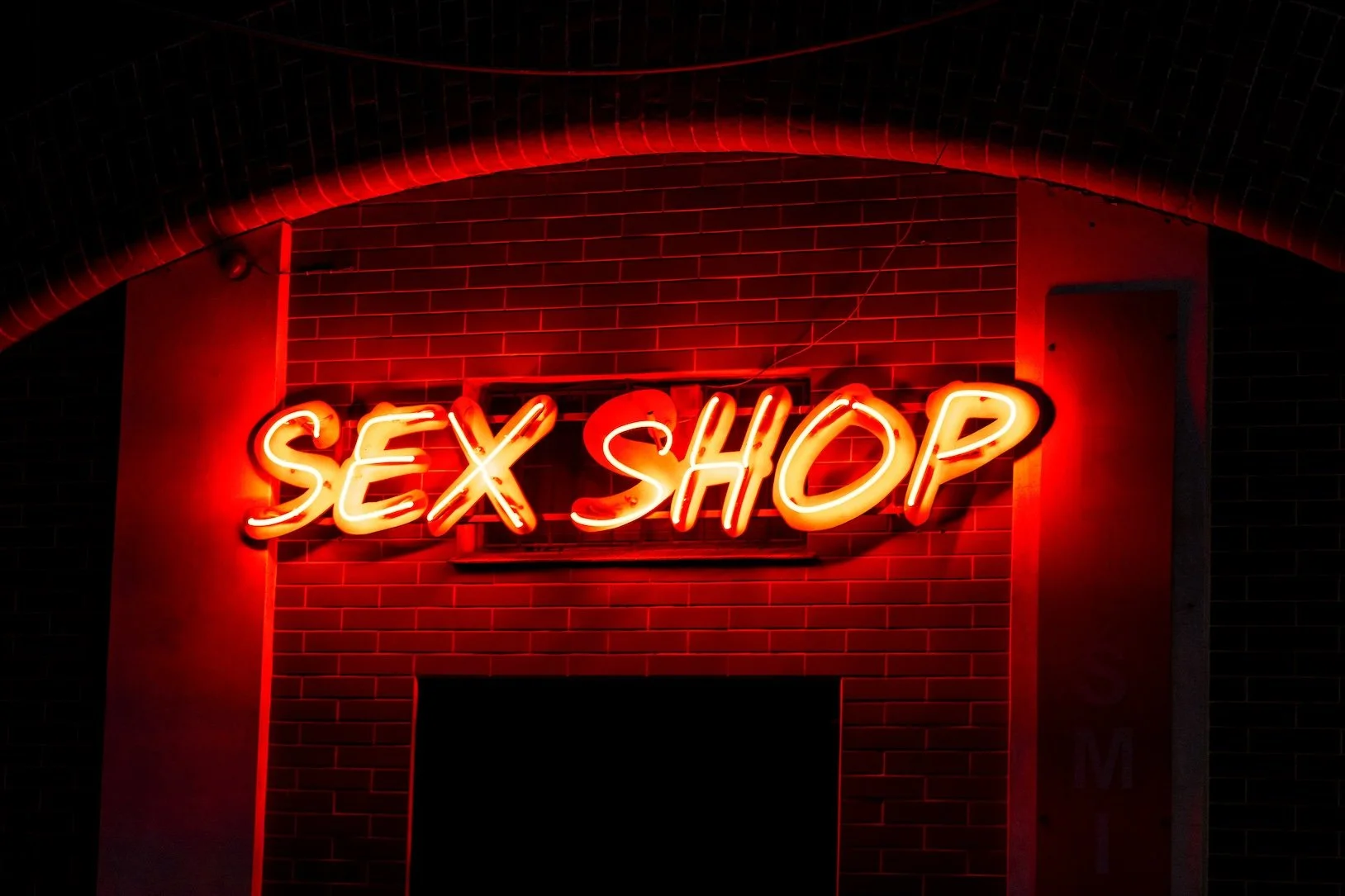 Eine Neon-Reklame zeigt den Schriftzug "Sex Shop" in rot.