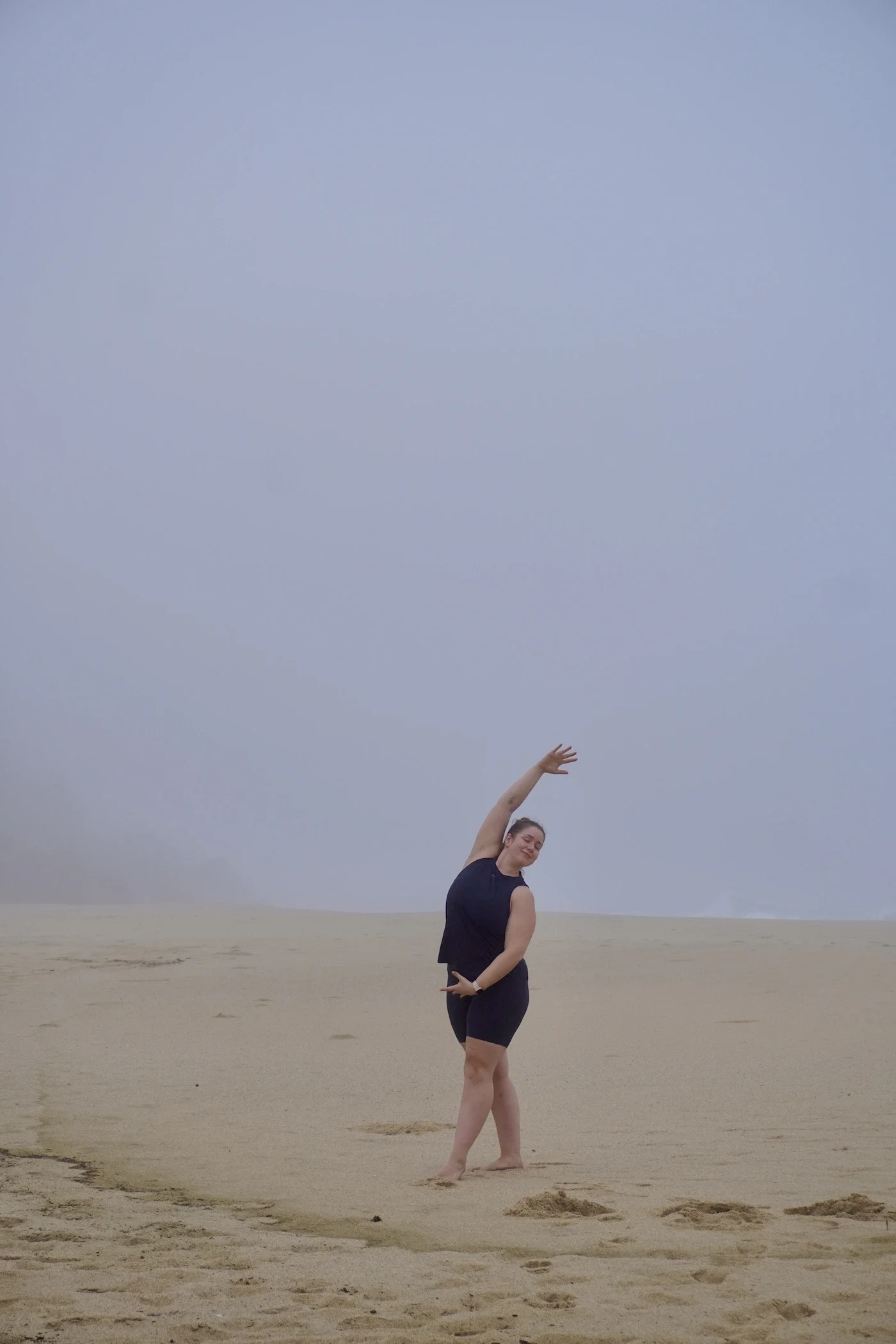 Die Yogalehrerin Lena Jungmann aus Berlin praktiziert Yoga an einem nebligen Strand