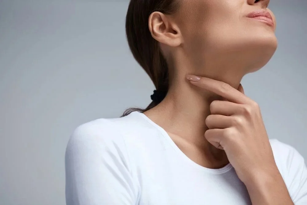 A woman is holding her hand below her jaw, indicating she might be thinking or considering something.