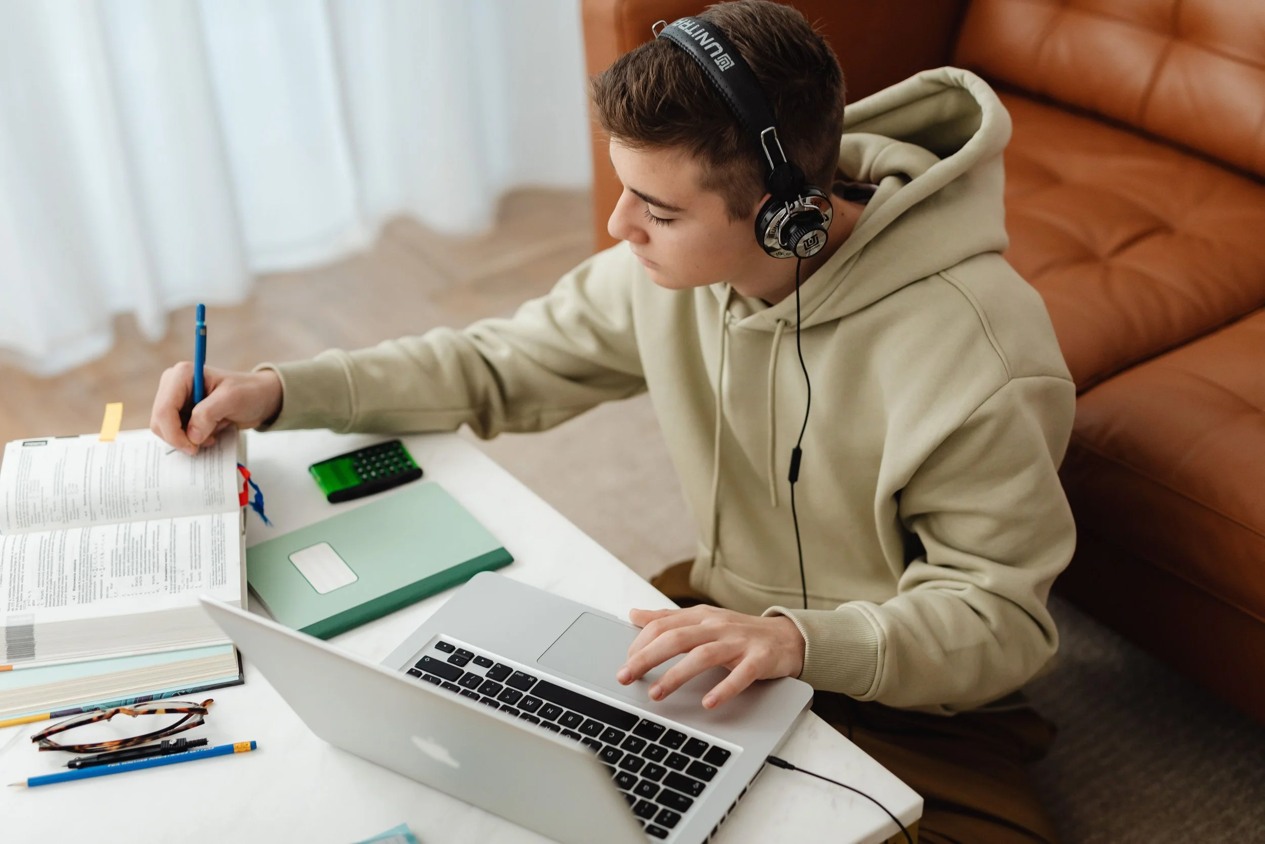 A virtual school student works in a textbook and their laptop