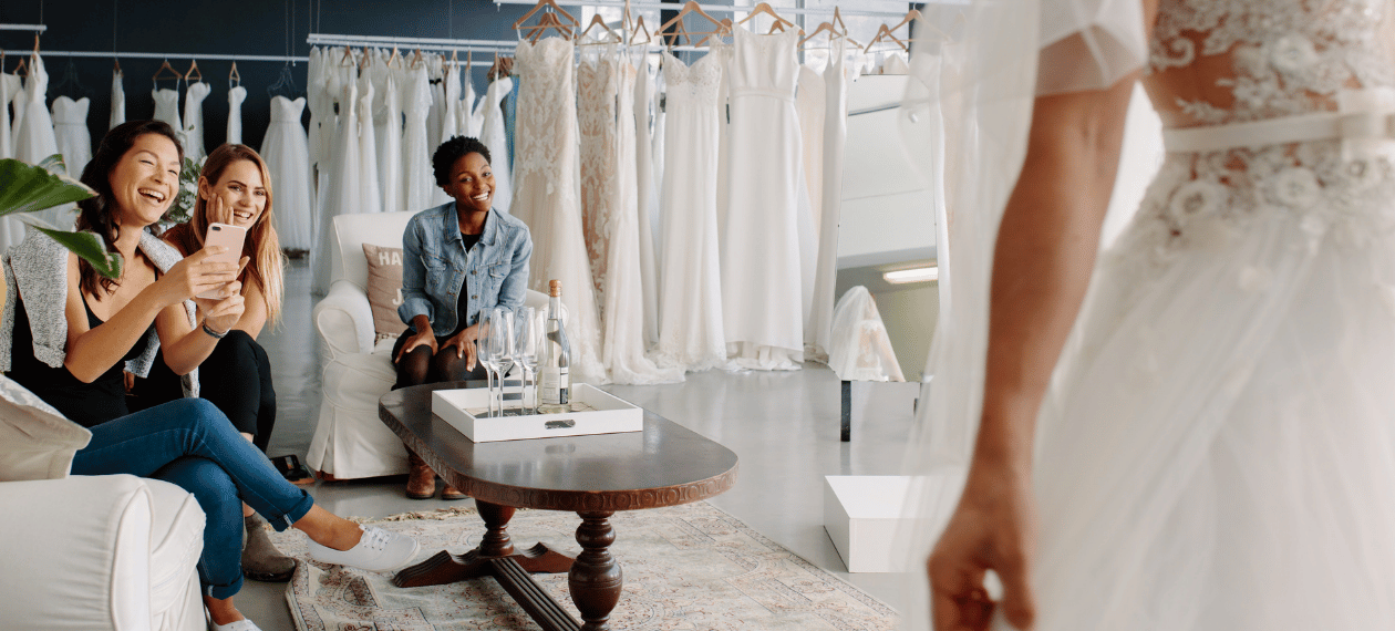Bride trying on a wedding dress while friends support her during a bridal appointment