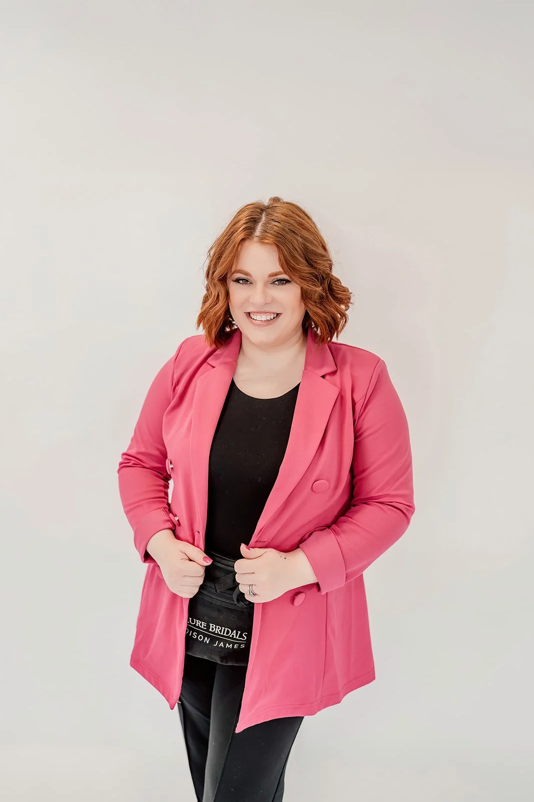 Chelsea K., lead bridal stylist at The Wedding Bell in Tacoma, smiling in front of bridal gowns.