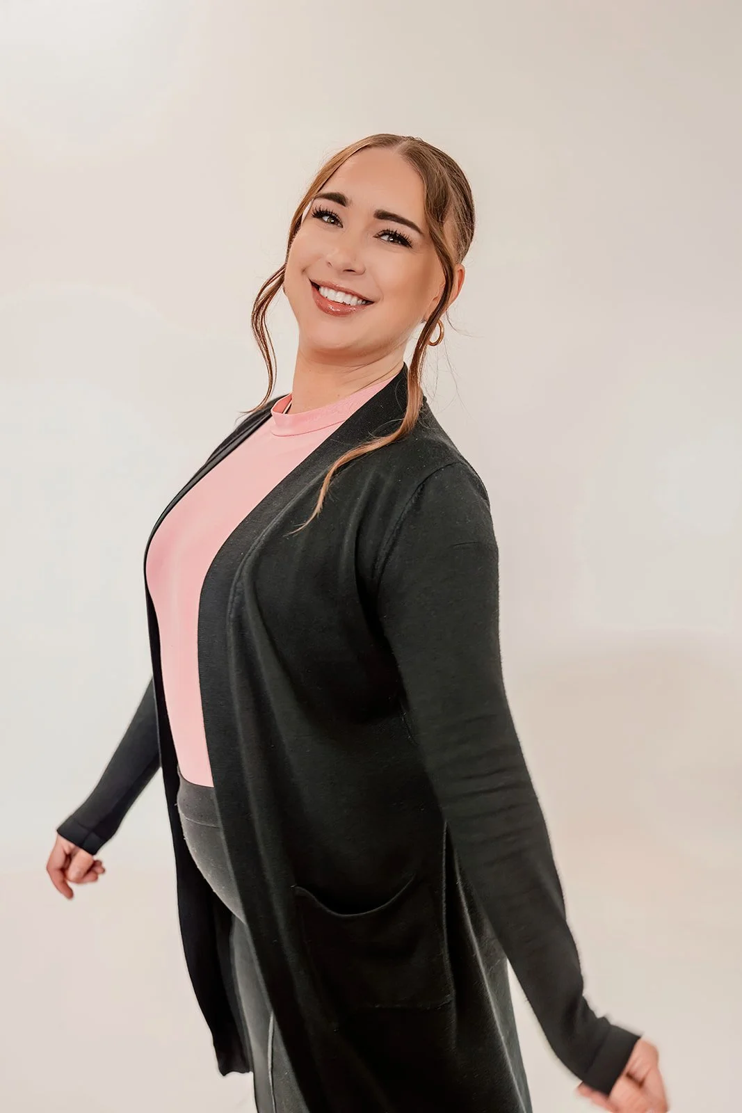 Alexa A., bridal stylist at The Wedding Bell in Tacoma, posing with wedding dresses in the background.