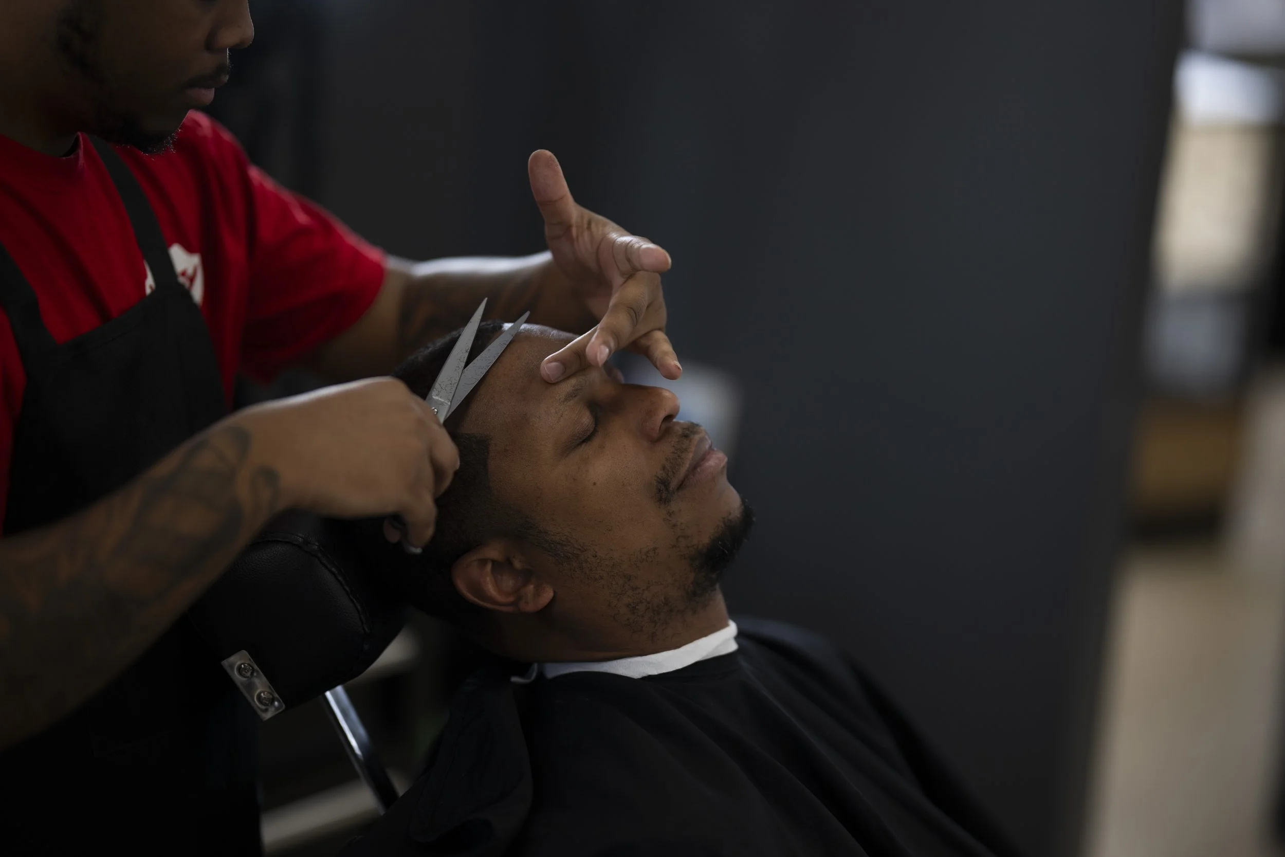 Barber using scissors to line up a mens hairline