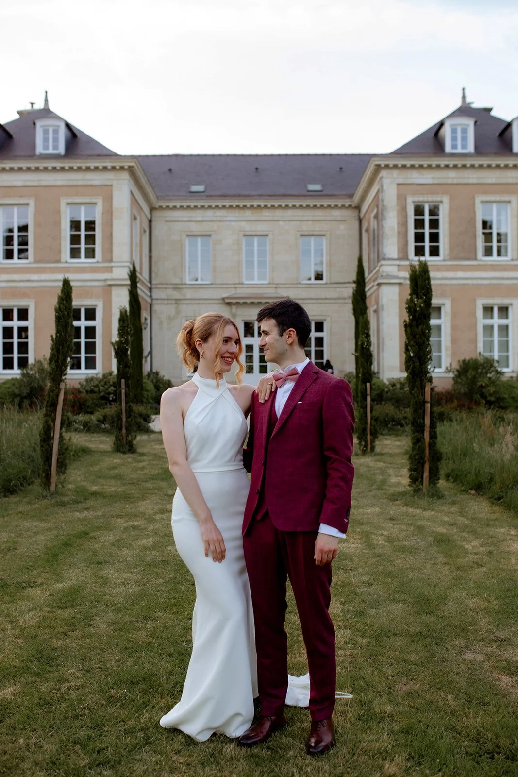 couple de mariés debout dans une allée devant un château