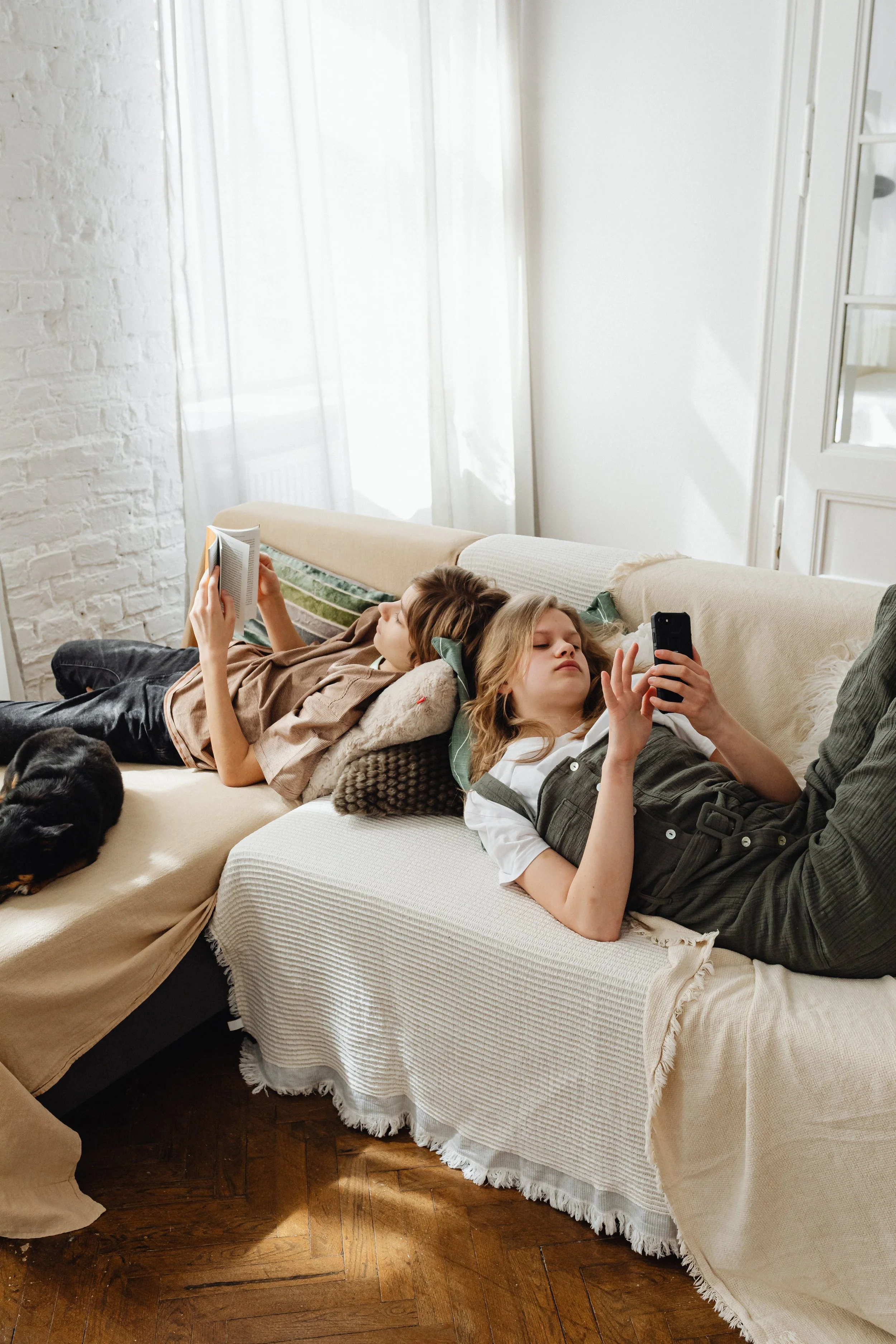 Two teens occupied on the couch.