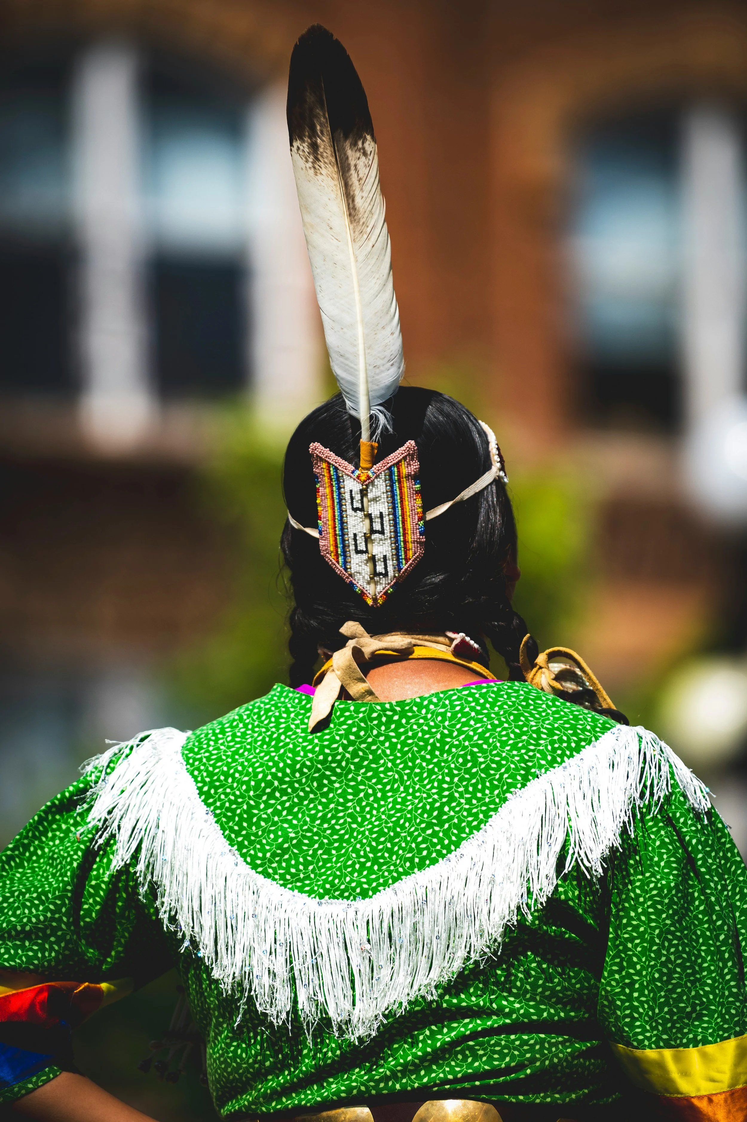 Photo of the back of a native american woman dressed in native american attire