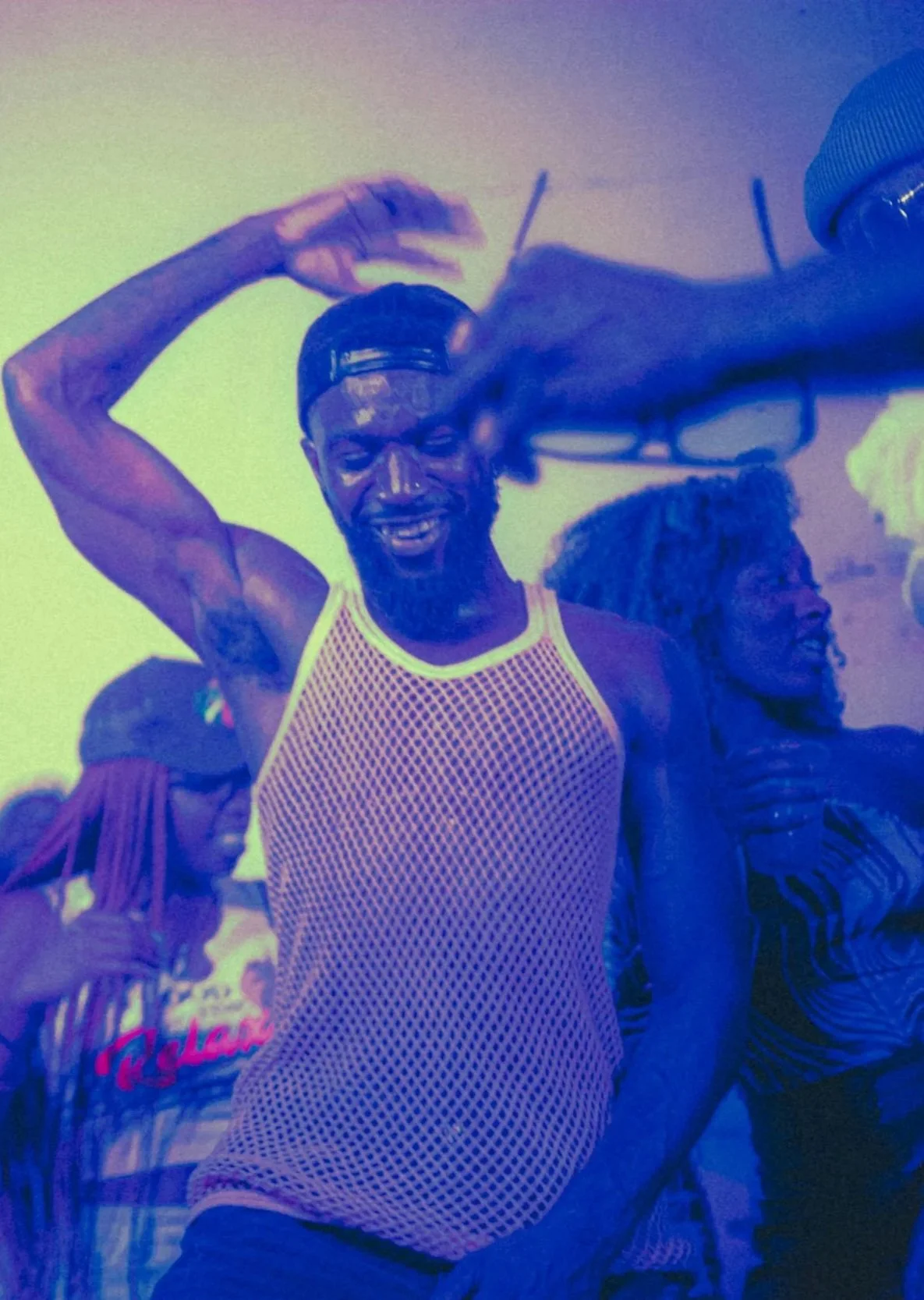 Black man dancing under blue and purple lights, capturing joy, movement, and connection in a crowded space.