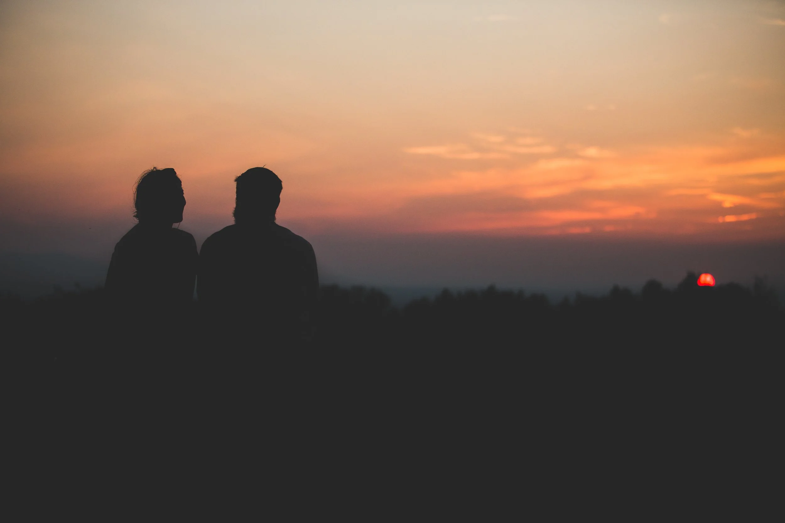 Two friends, a man and a woman, sitting together watching the sunset