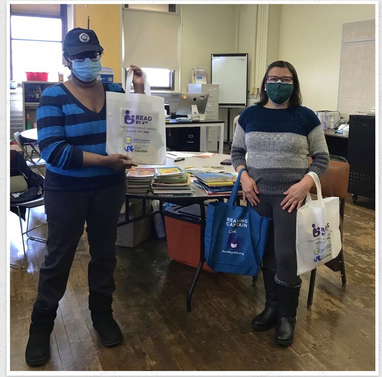 Mary Wilson and Deicy Perez from Beyond Literacy distributing bags of books and materials to families.