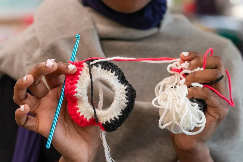 Girl shows off crochet project.