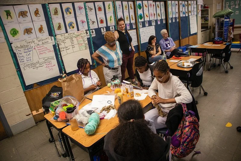 Students work on crochet projects in classroom.