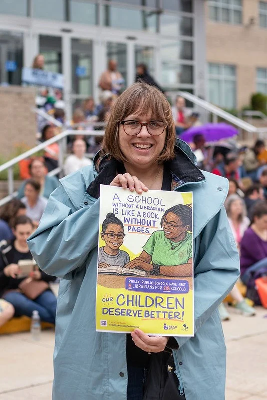 Jenny Lowman proudly holds a poster at the Philly Read-In, rallying to restore school librarians.