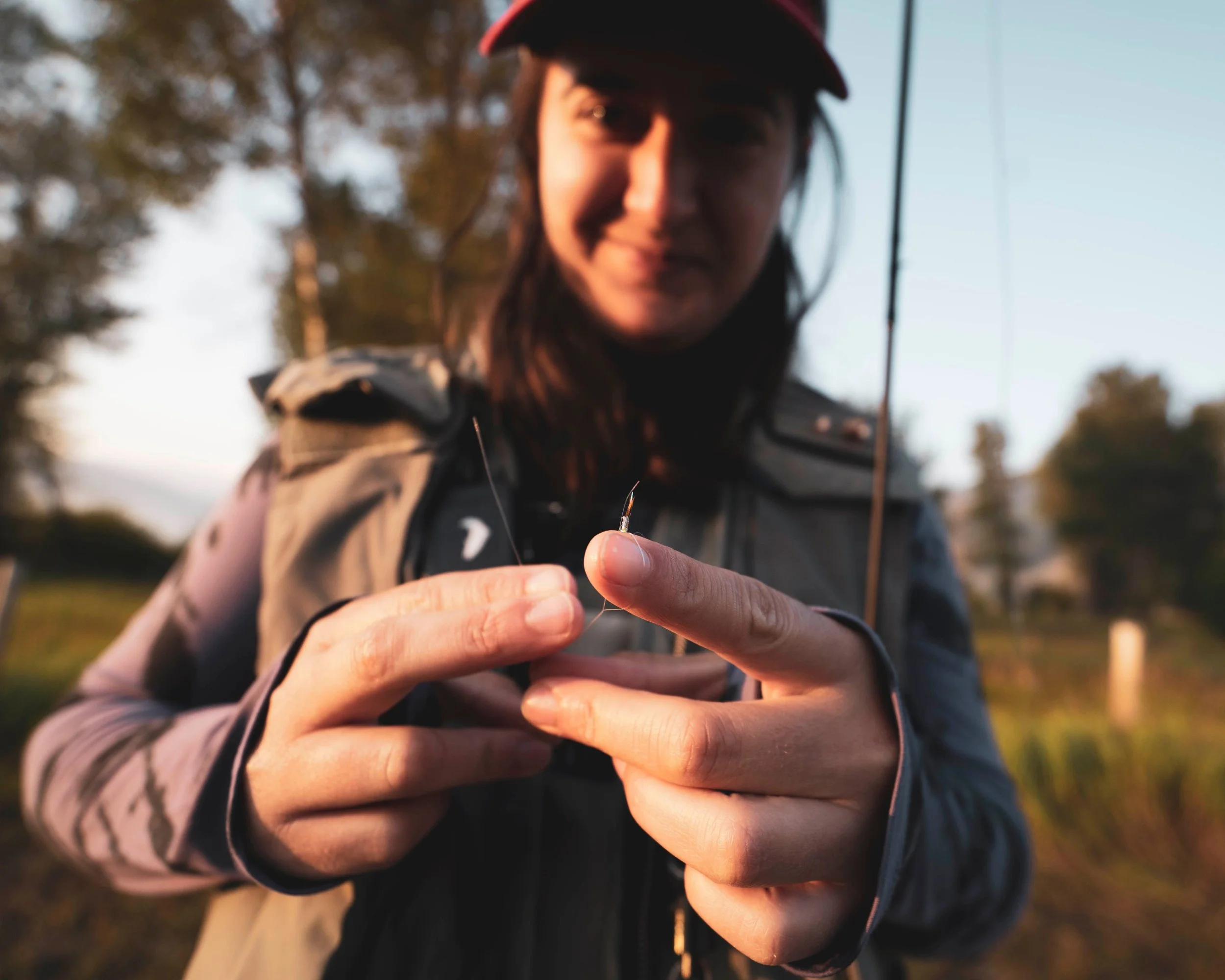 anglers Michelle (she/her) holds up the end of her tippet in the morning light