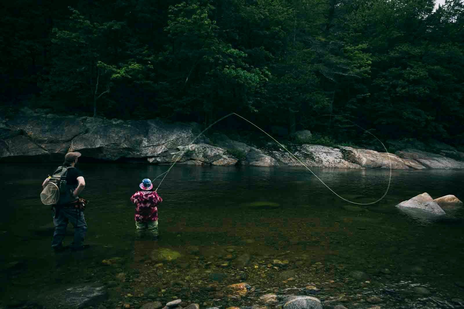  Zsakee (she/her) and Jared (he/him) look out over the Wild River, fly line in air. Photo:  Joe Klementovich  