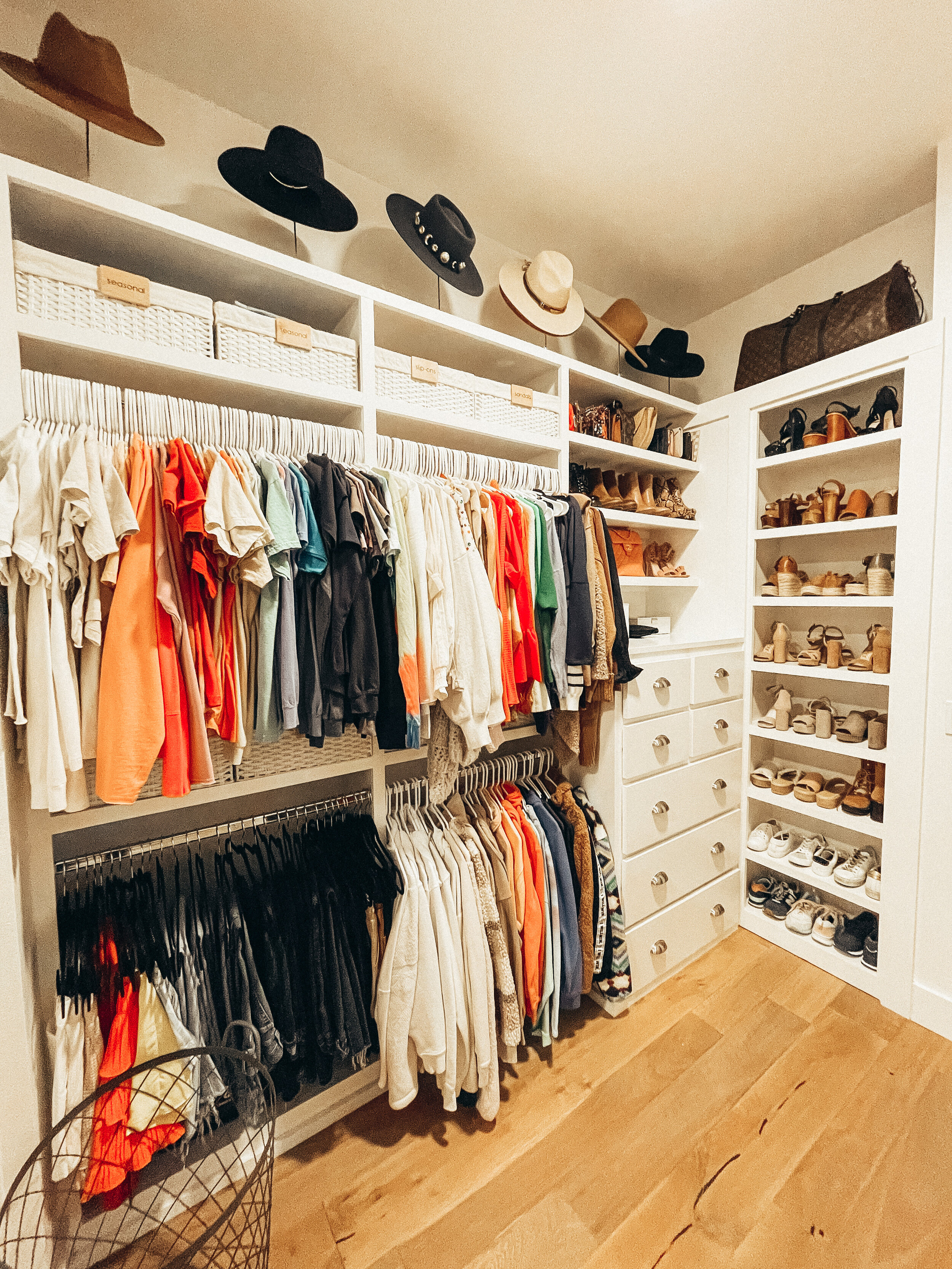 Walk-in closet with clothes and shelves organized by Stay Golden Organizing