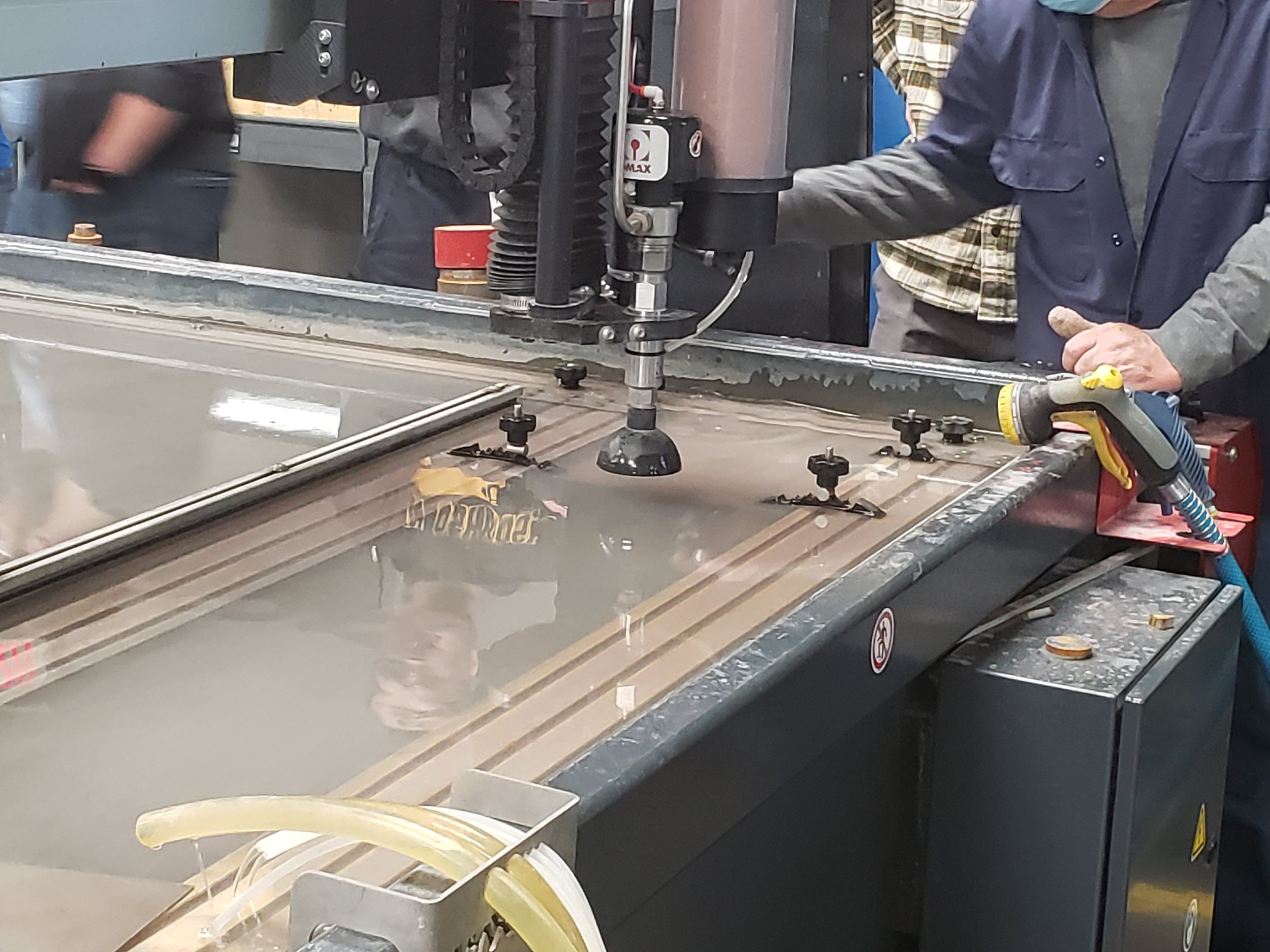Using the water jet to cut the reciprocating plate out of quarter inch steel, with the help of machinist Patrick David.