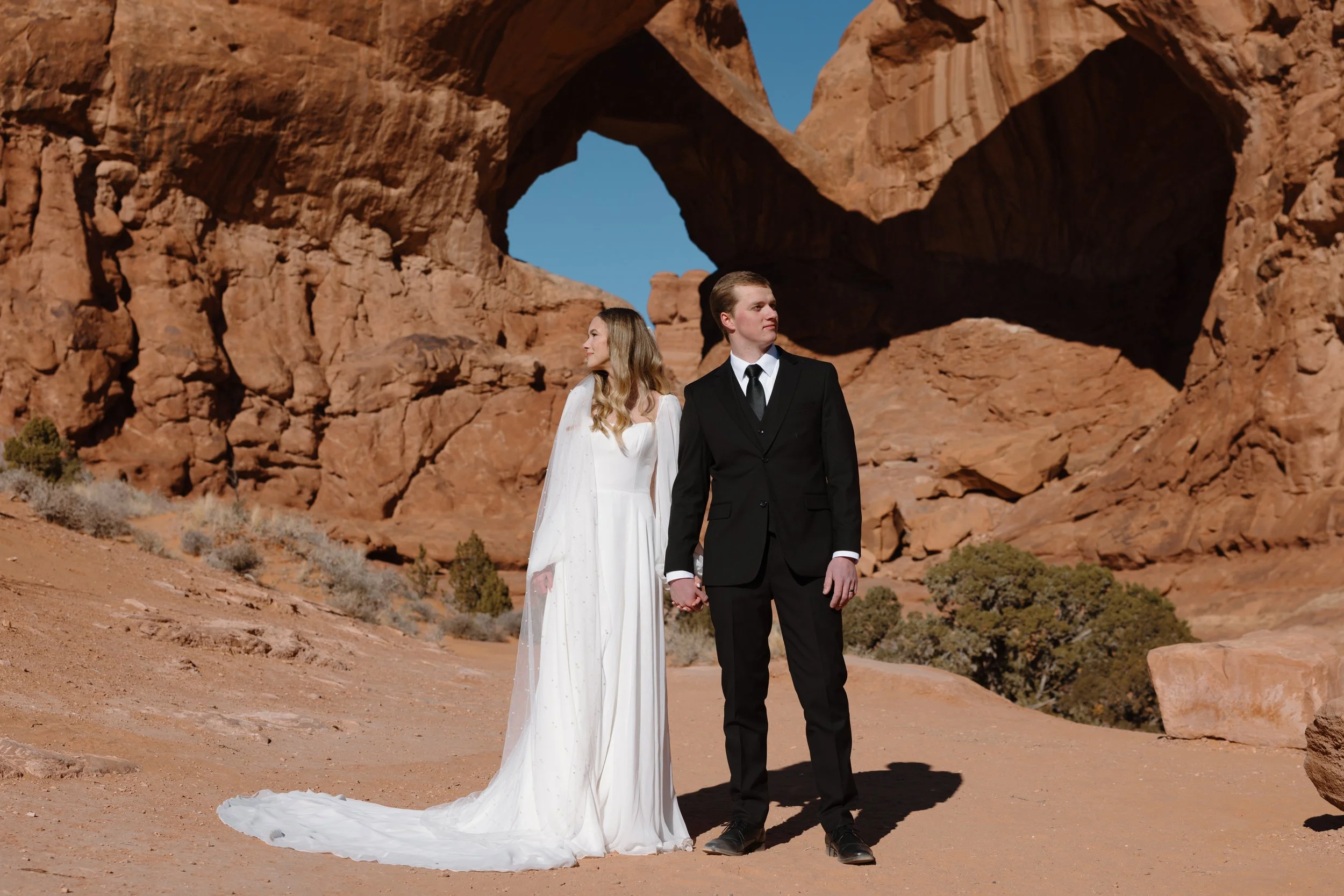 Moab Utah adventure elopement photographer, bride and groom portrait under natural red rock arch, Arches National Park area