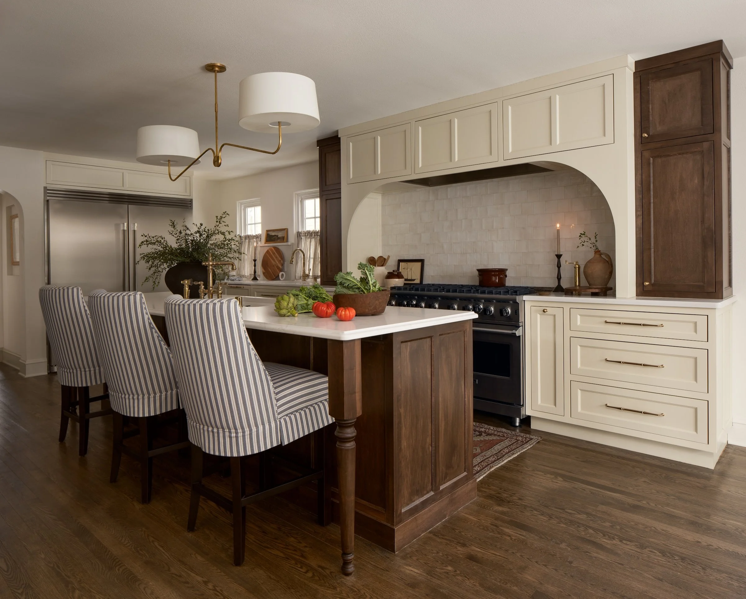 Kitchen with island, striped chairs, white cabinets, dark wood accents, stove, and decorative items.