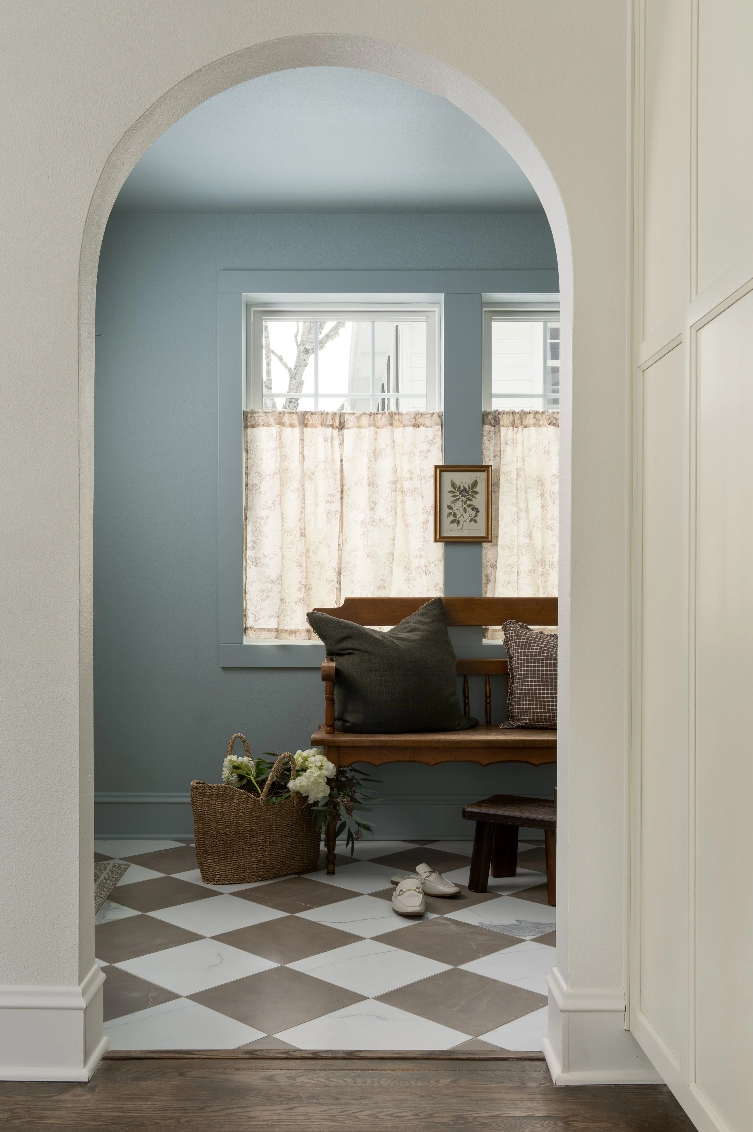 Whitefish Bay Tudor mudroom with arched doorway, styled with a bench